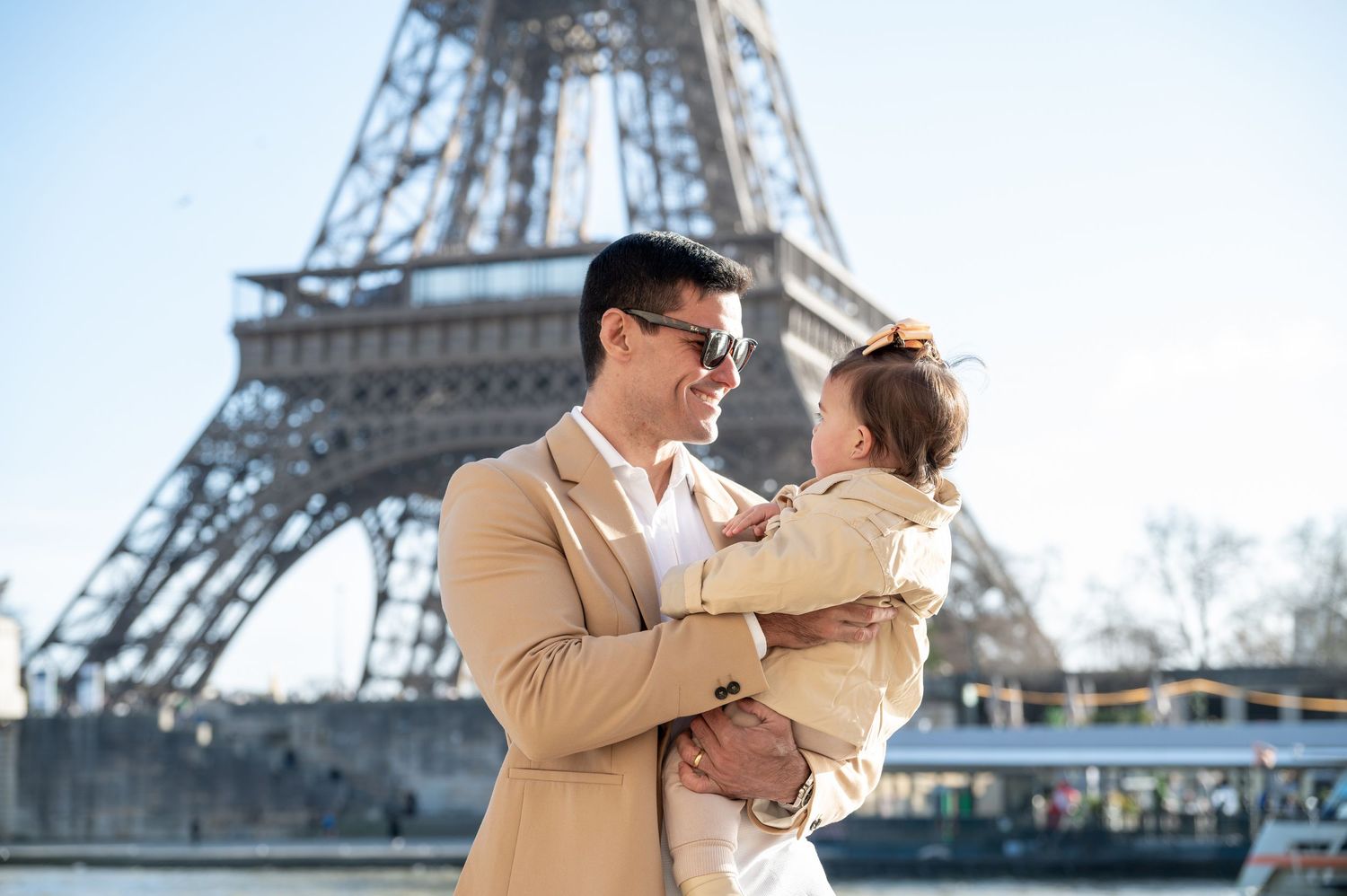 A joyful moment shared between two people in front of the iconic Eiffel Tower in Paris on a sunny day.