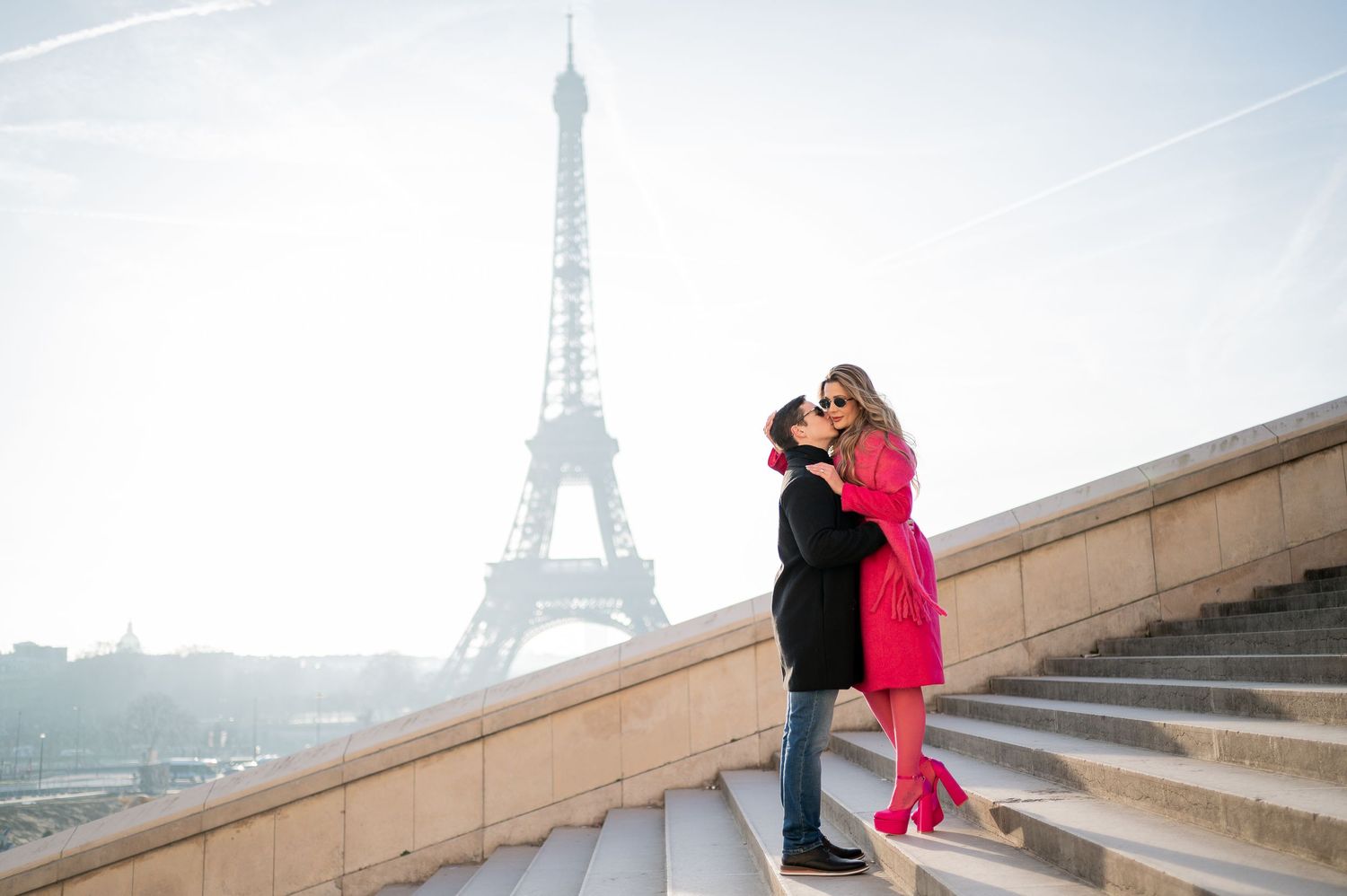Couple embracing on steps at Trocadero with Eiffel Tower creating perfect Parisian backdrop.