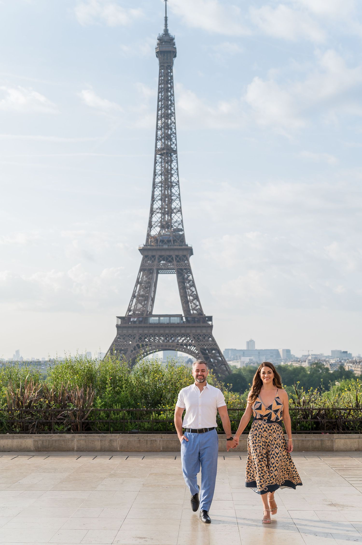 A romantic photoshoot session at the Eiffel Tower in Paris showing couple strolling across Trocadero Plaza on a sunny day.