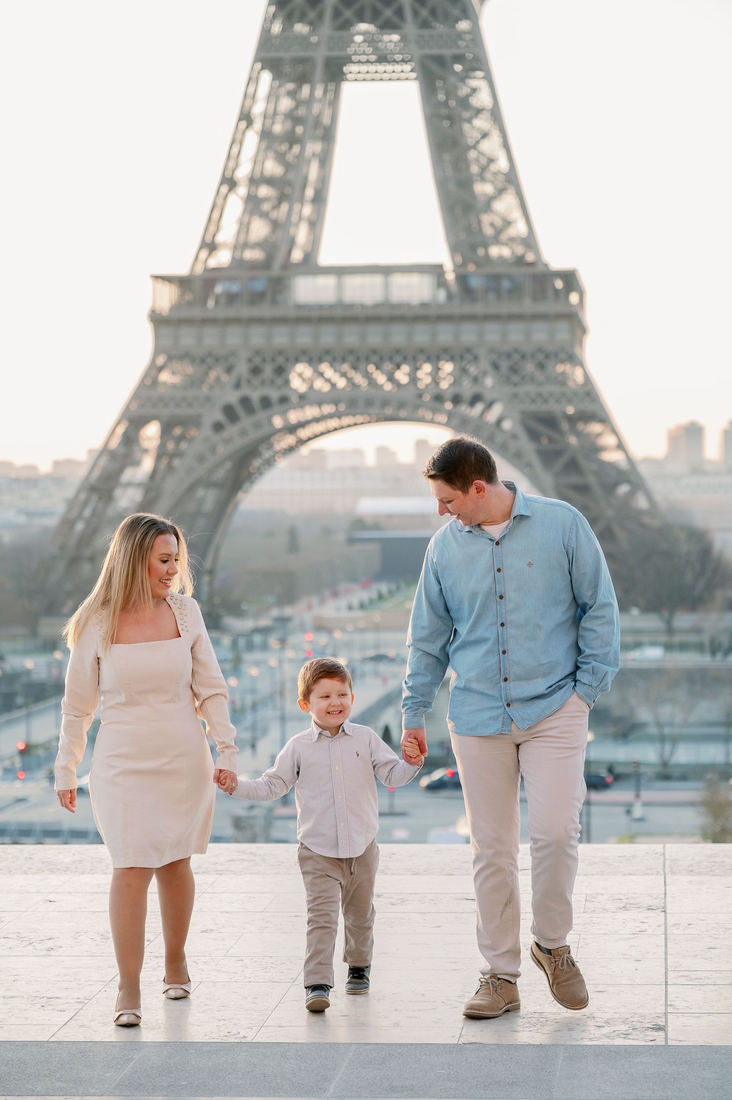 Family walking together on Trocadero plaza with Eiffel Tower backdrop.