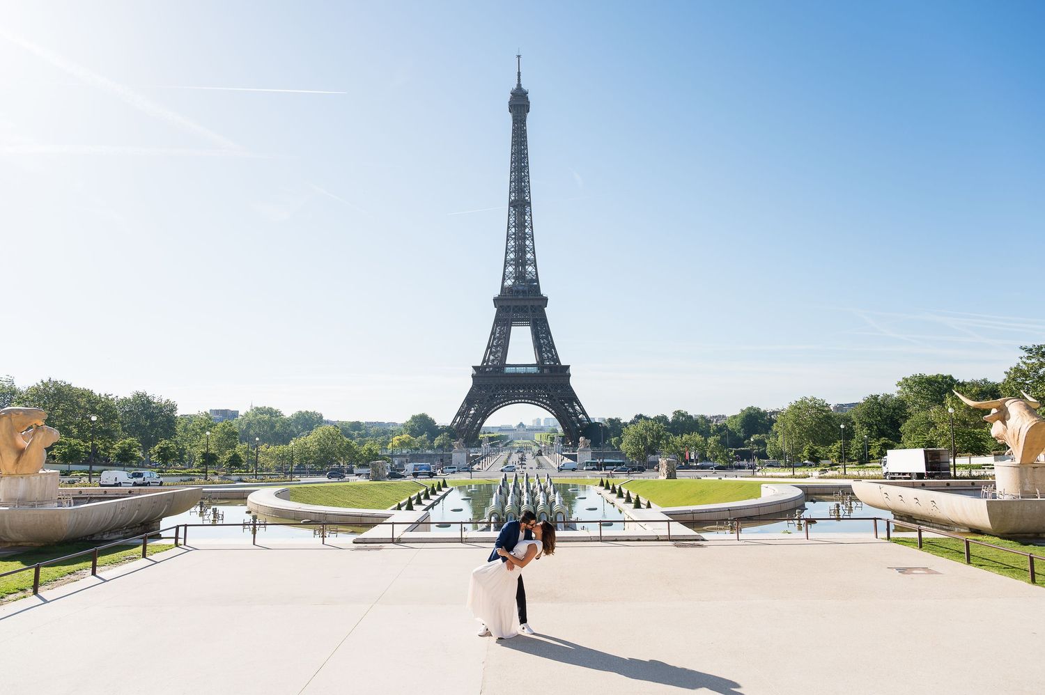 Couple embracing in front of the Eiffel Tower on a sunny day at Trocadero plaza in Paris, France.