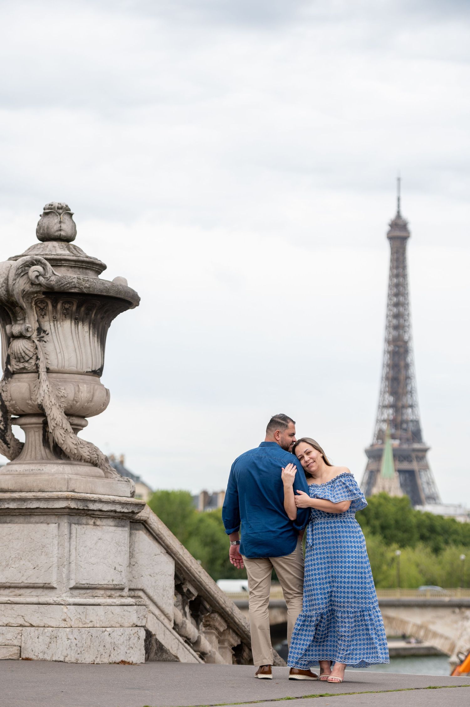 A couple shares a romantic moment on the Pont Alexandre III bridge with the iconic Eiffel Tower in the background in Paris.