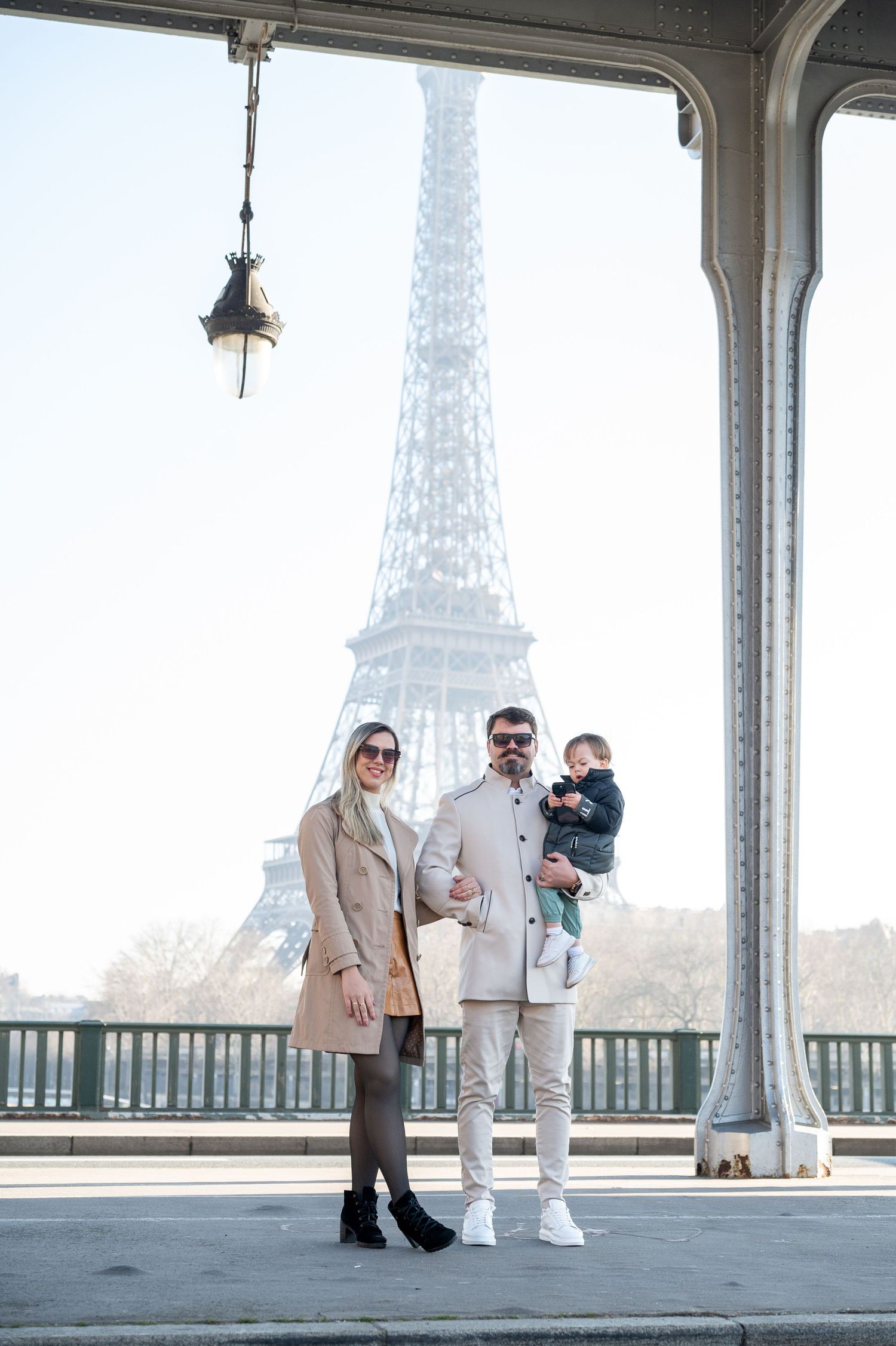 Stylish family portrait under covered walkway with Eiffel Tower view in Paris.