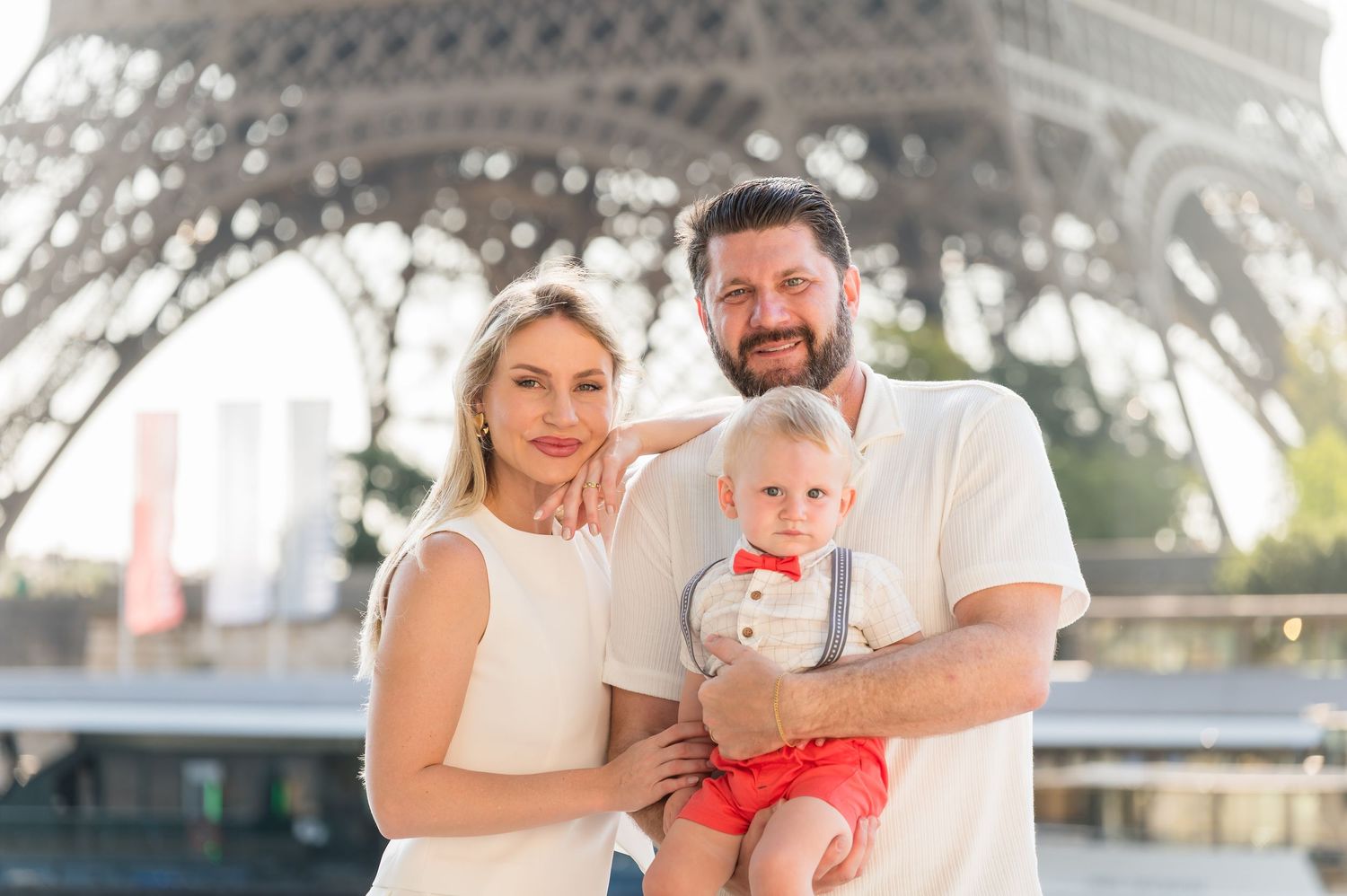 A group of Paris tourists smile and celebrate in front of the iconic Eiffel Tower.