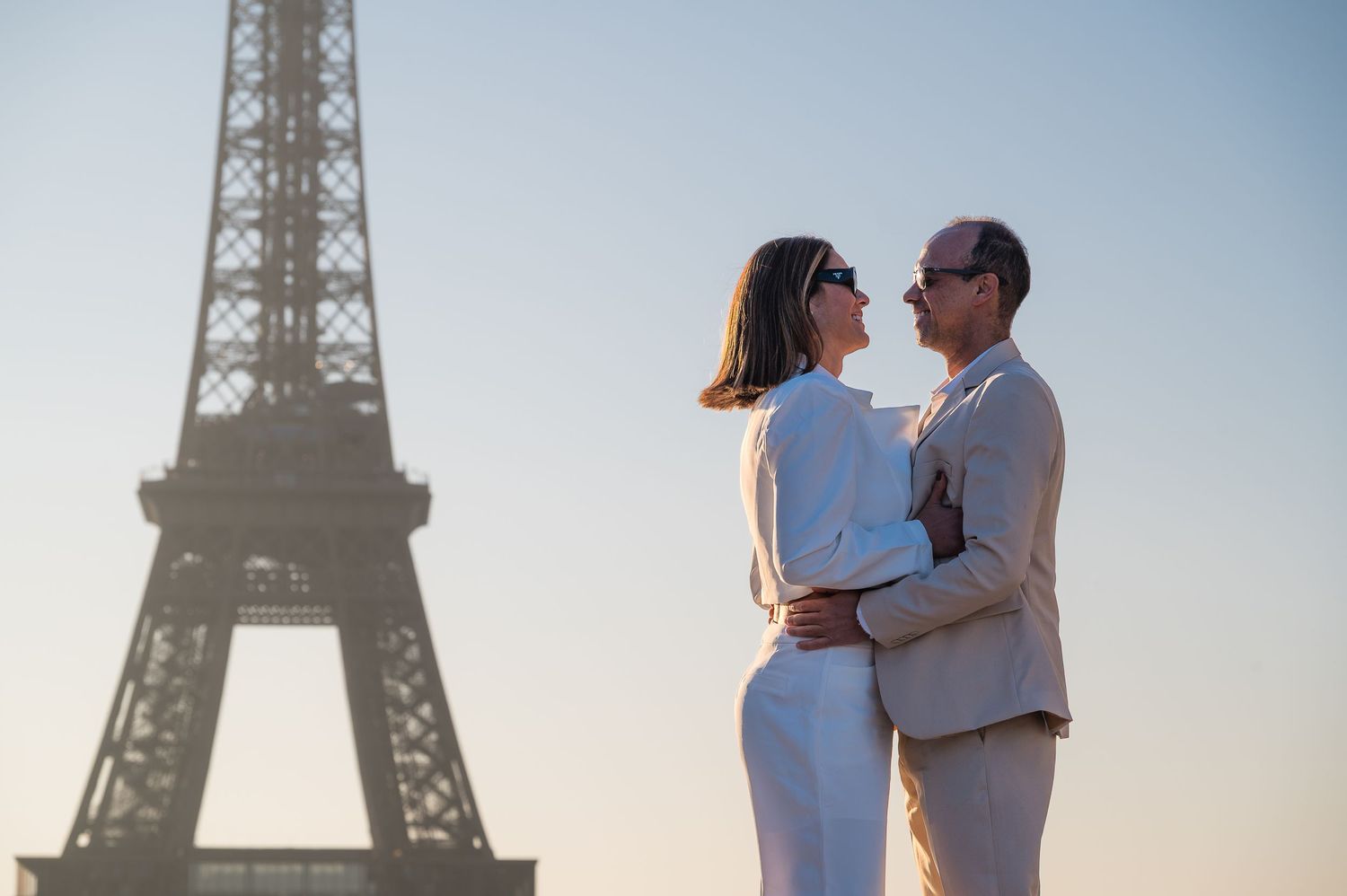A romantic couple pose against the iconic Eiffel Tower during a golden hour photoshoot in Paris.