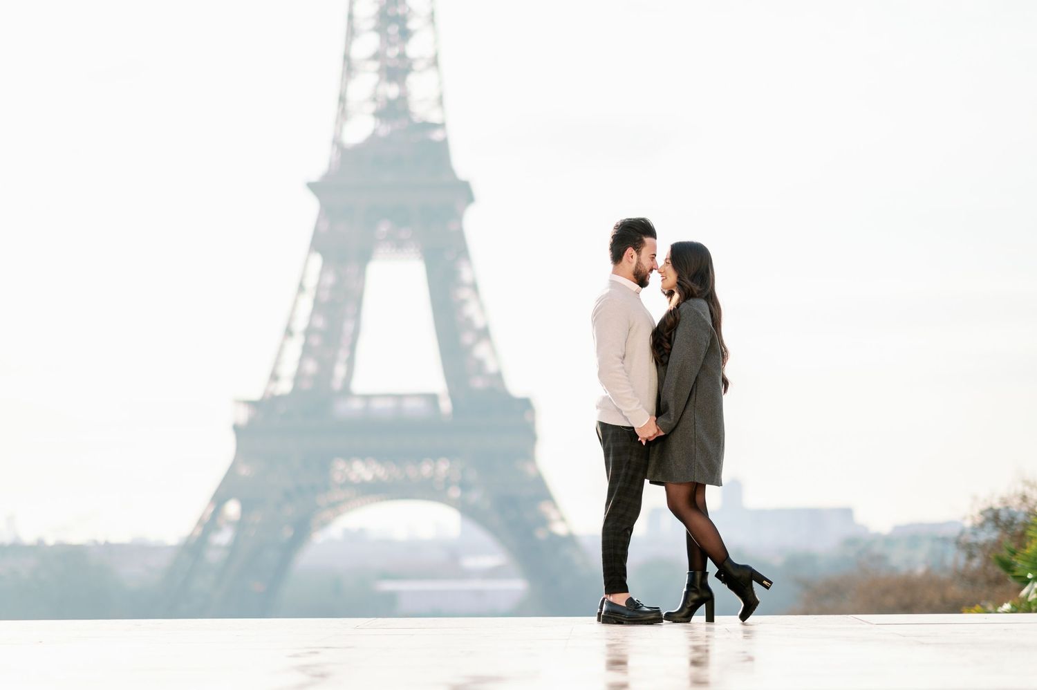 A romantic couple stands silhouetted against the Eiffel Tower at dusk.