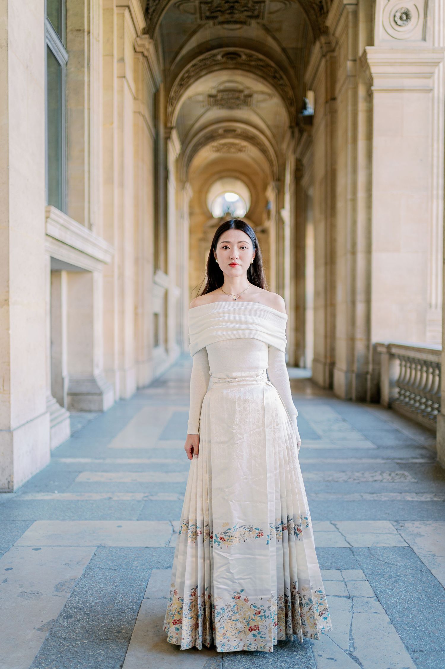 White formal dress captured in an ornate architectural walkway with vaulted ceilings.