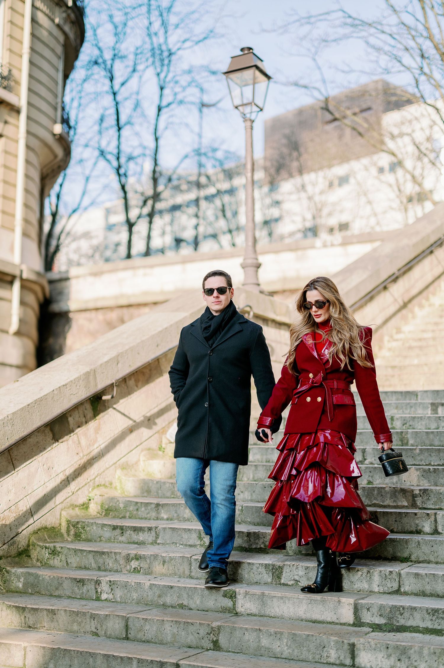 Romantic couple walking down historic stone steps in Paris with vintage lamp post.