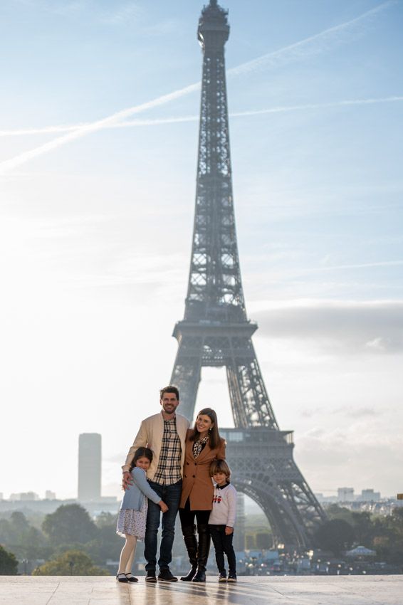 Tourists stand together in front of the iconic Eiffel Tower in Paris on a bright autumn day.
