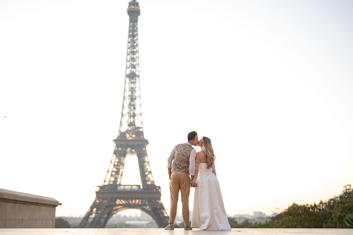 A couple in romantic pose at sunset with the iconic Eiffel Tower in the background in Paris, France.