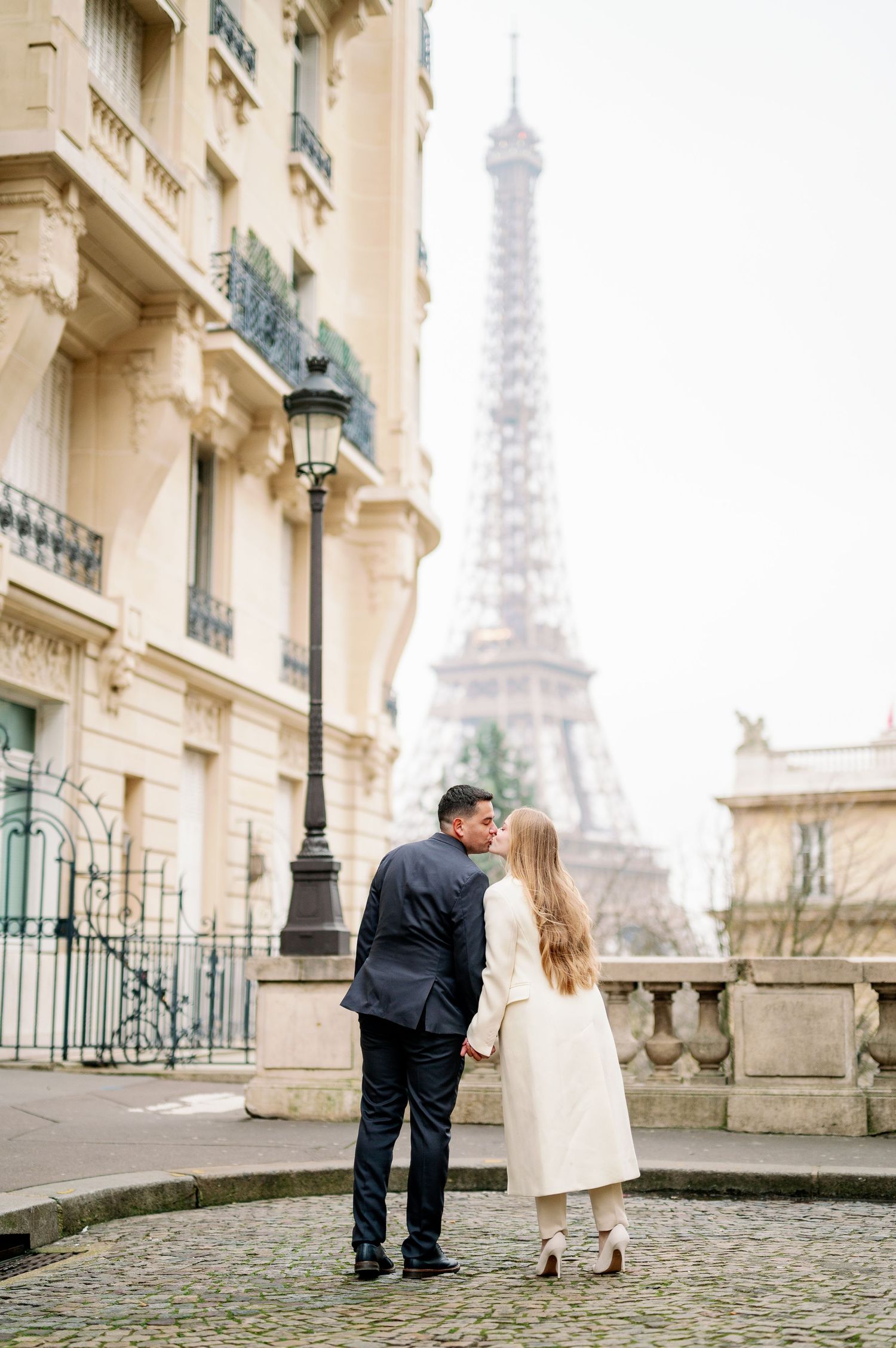 Romantic couple admiring Eiffel Tower view from classic Parisian street corner.