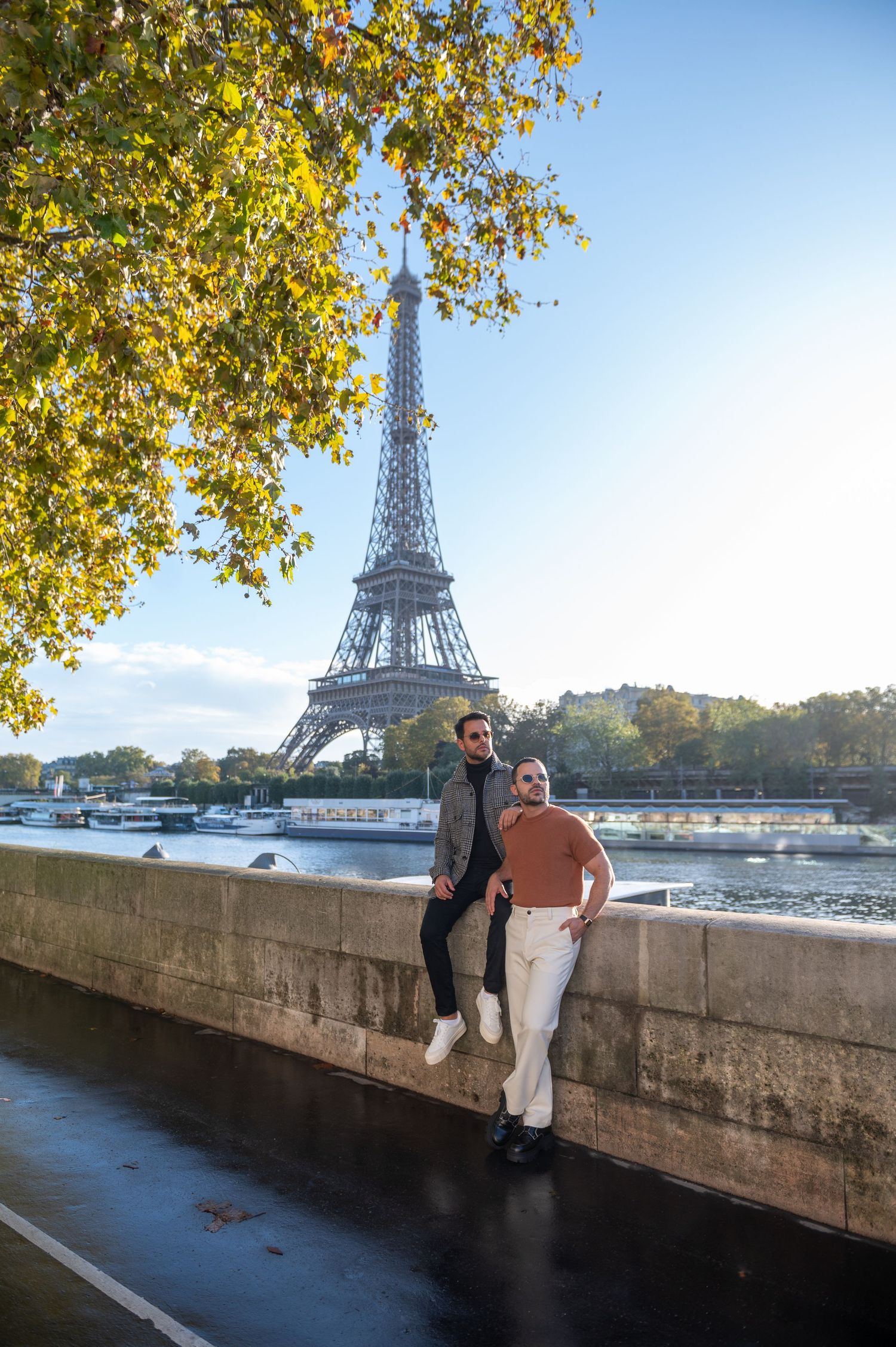 Autumn scene along the Seine River in Paris with the iconic Eiffel Tower rising above fall foliage.