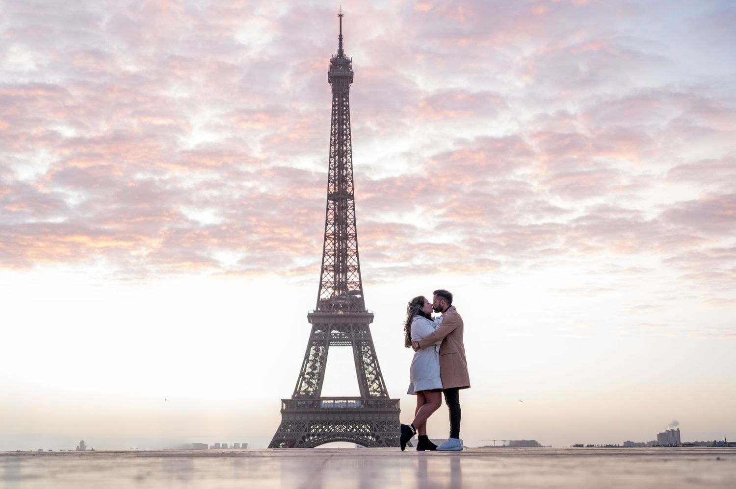 A couple sharing a romantic moment in front of the Eiffel Tower during a beautiful sunset in Paris.