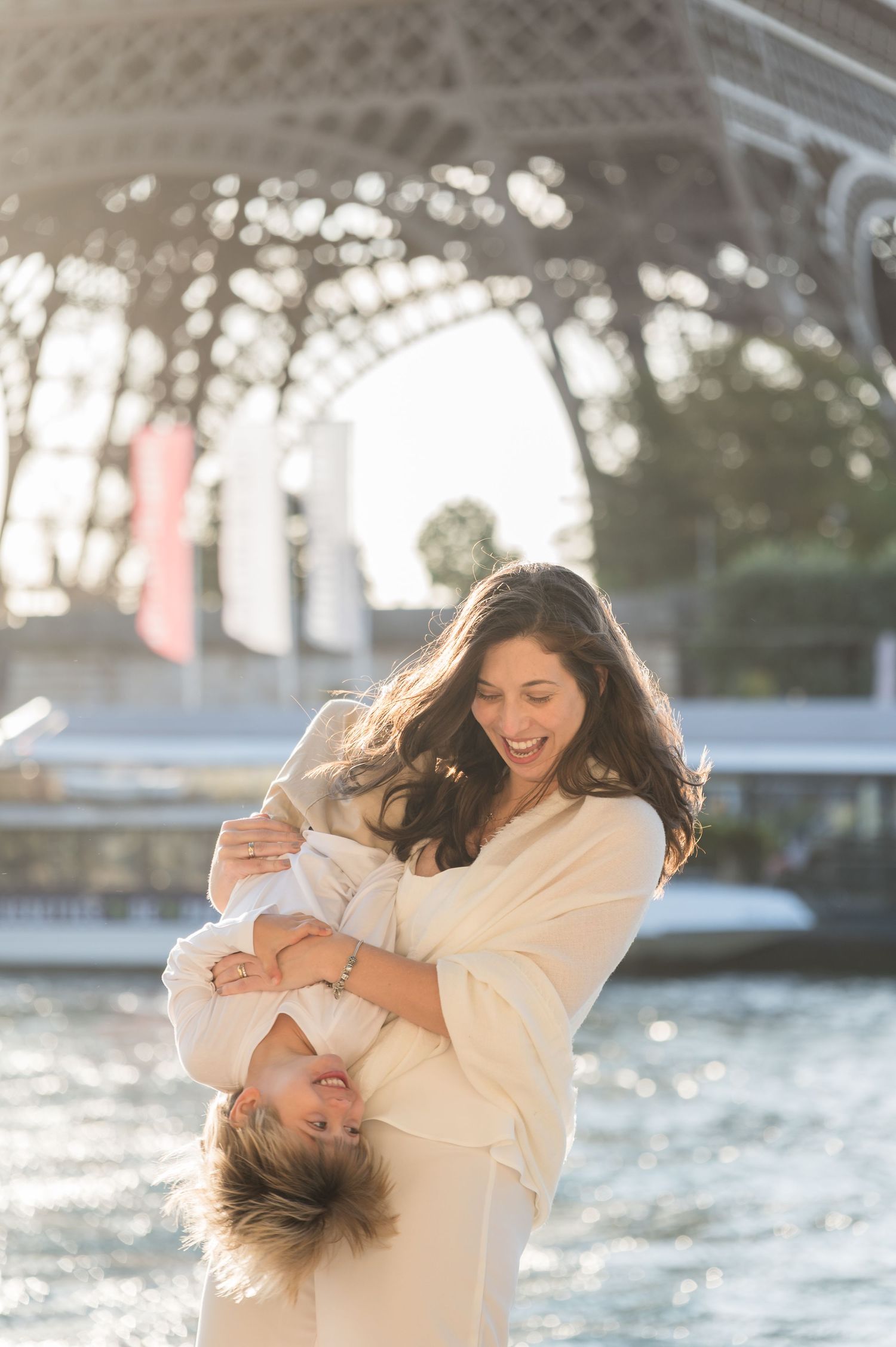 Joyful playful moments captured by the water with sun sparkling on gentle waves in the background.