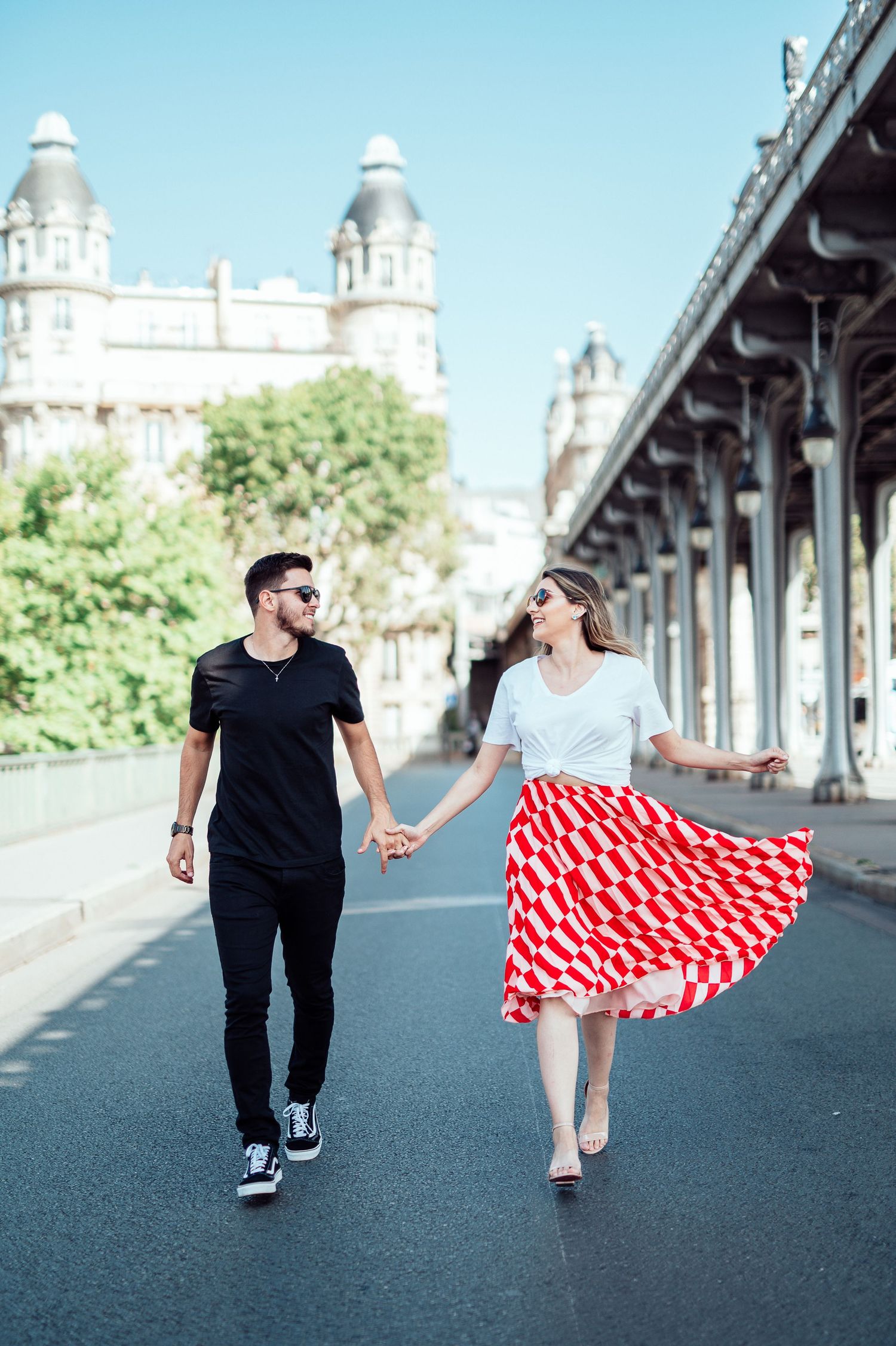 A couple walks along Bir-Hakeim Bridge in Paris as a red polka dot dress flows in the breeze.