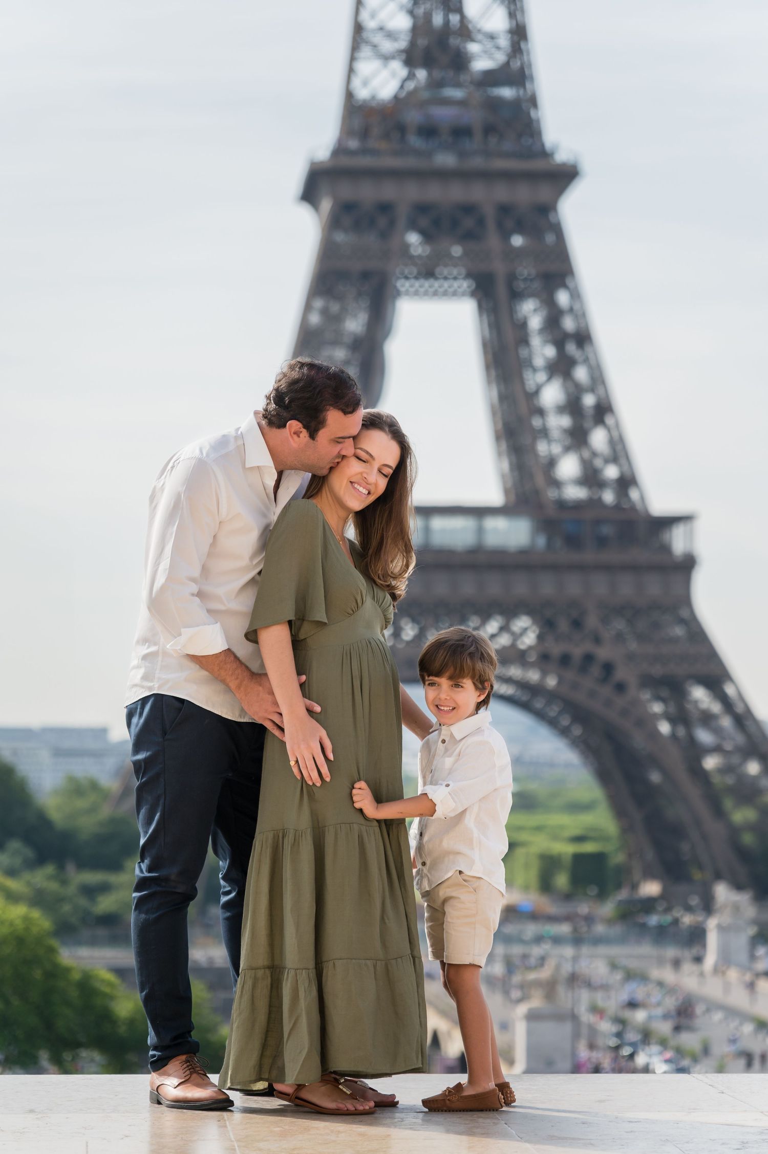 Family sharing an intimate moment together in front of the iconic Eiffel Tower in Paris.