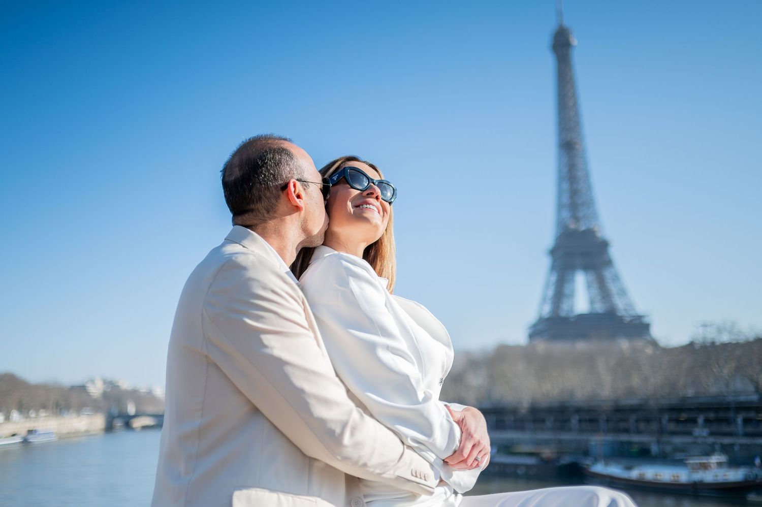 A romantic embrace on a sunny day with the iconic Eiffel Tower creating a perfect Parisian backdrop.
