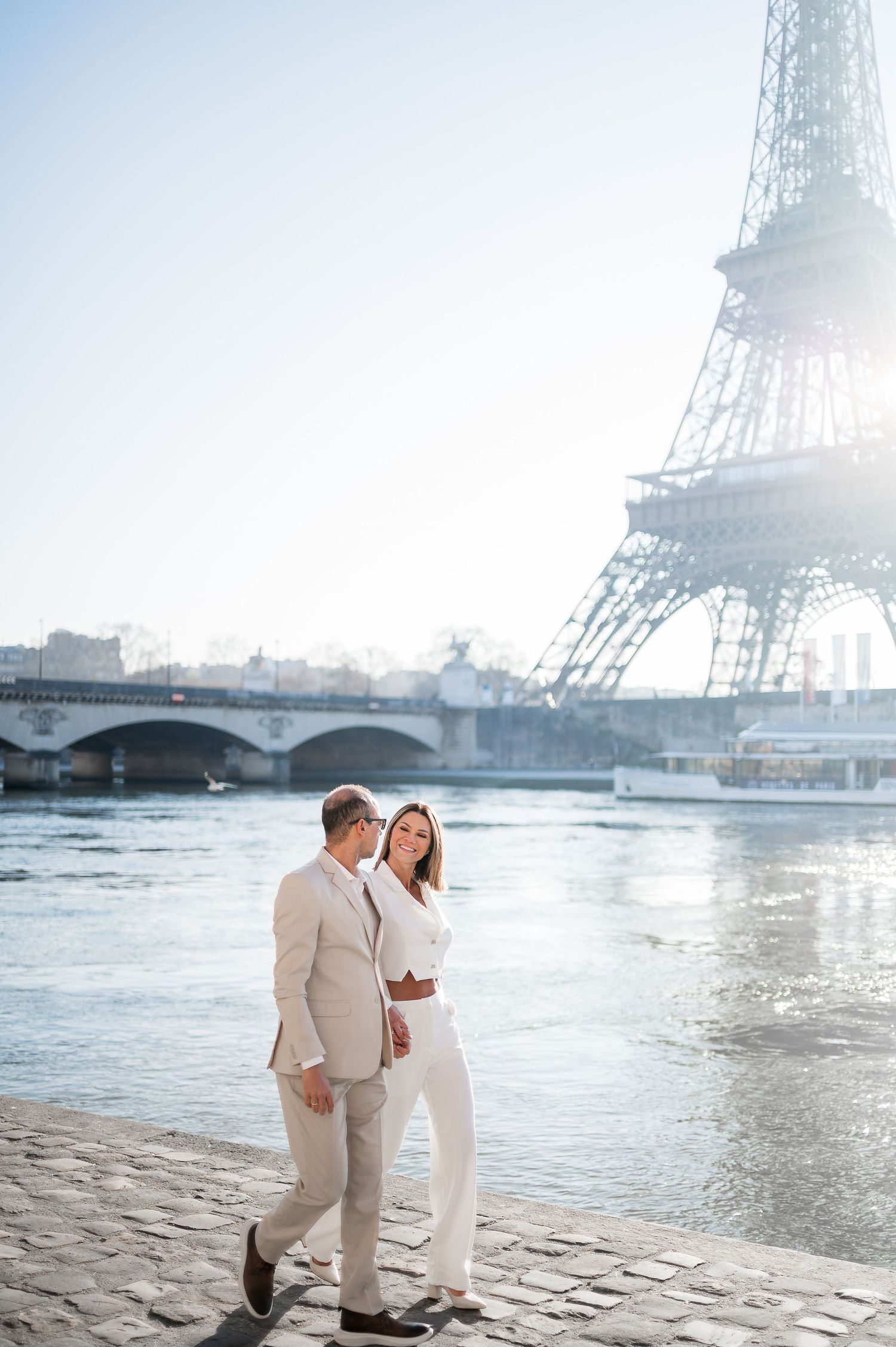 A couple strolling along the Seine River with the Eiffel Tower creating a romantic Parisian backdrop.