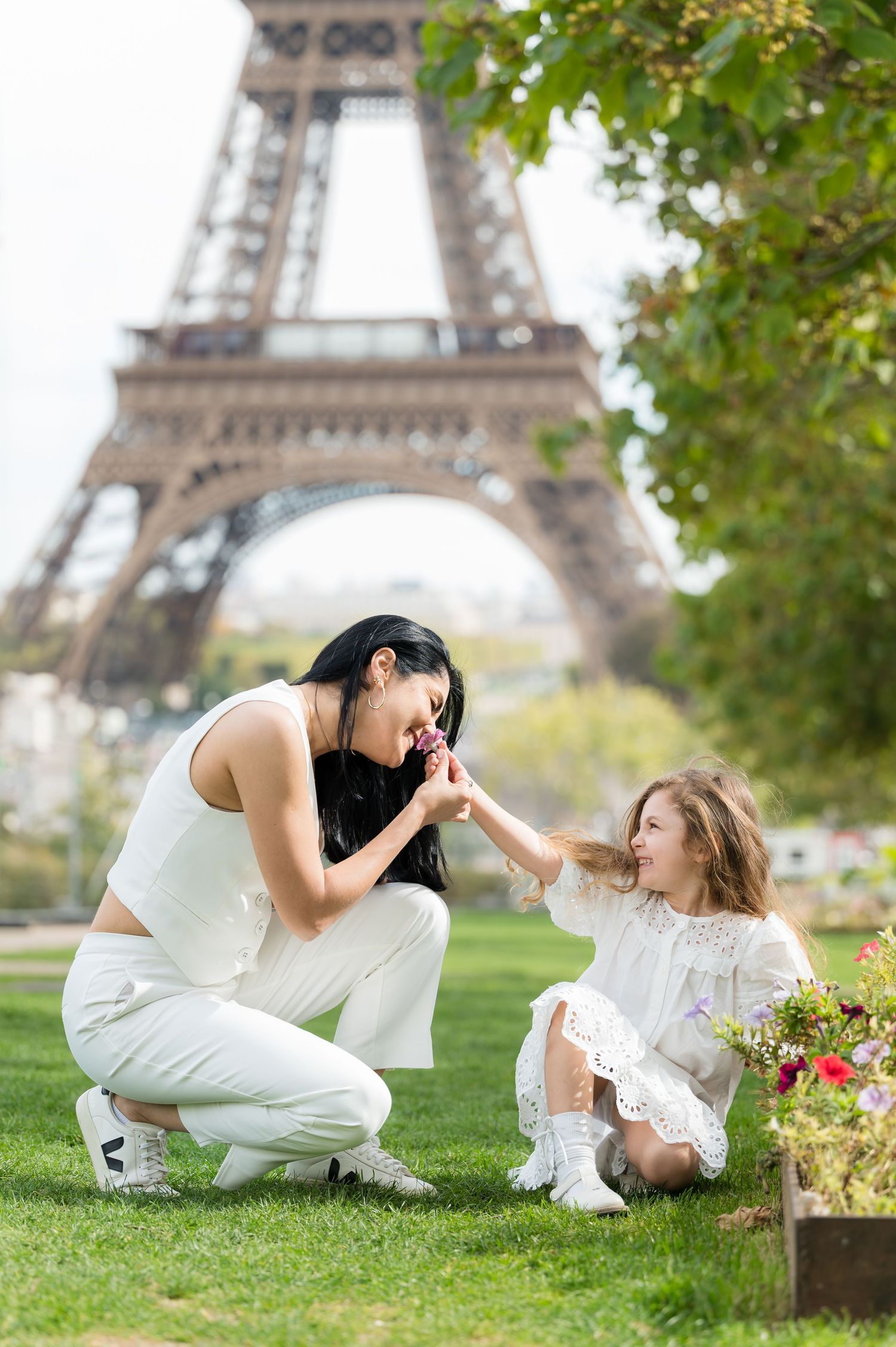 Playful moments captured in a series of photos at the Eiffel Tower with people in white outfits on the grass.
