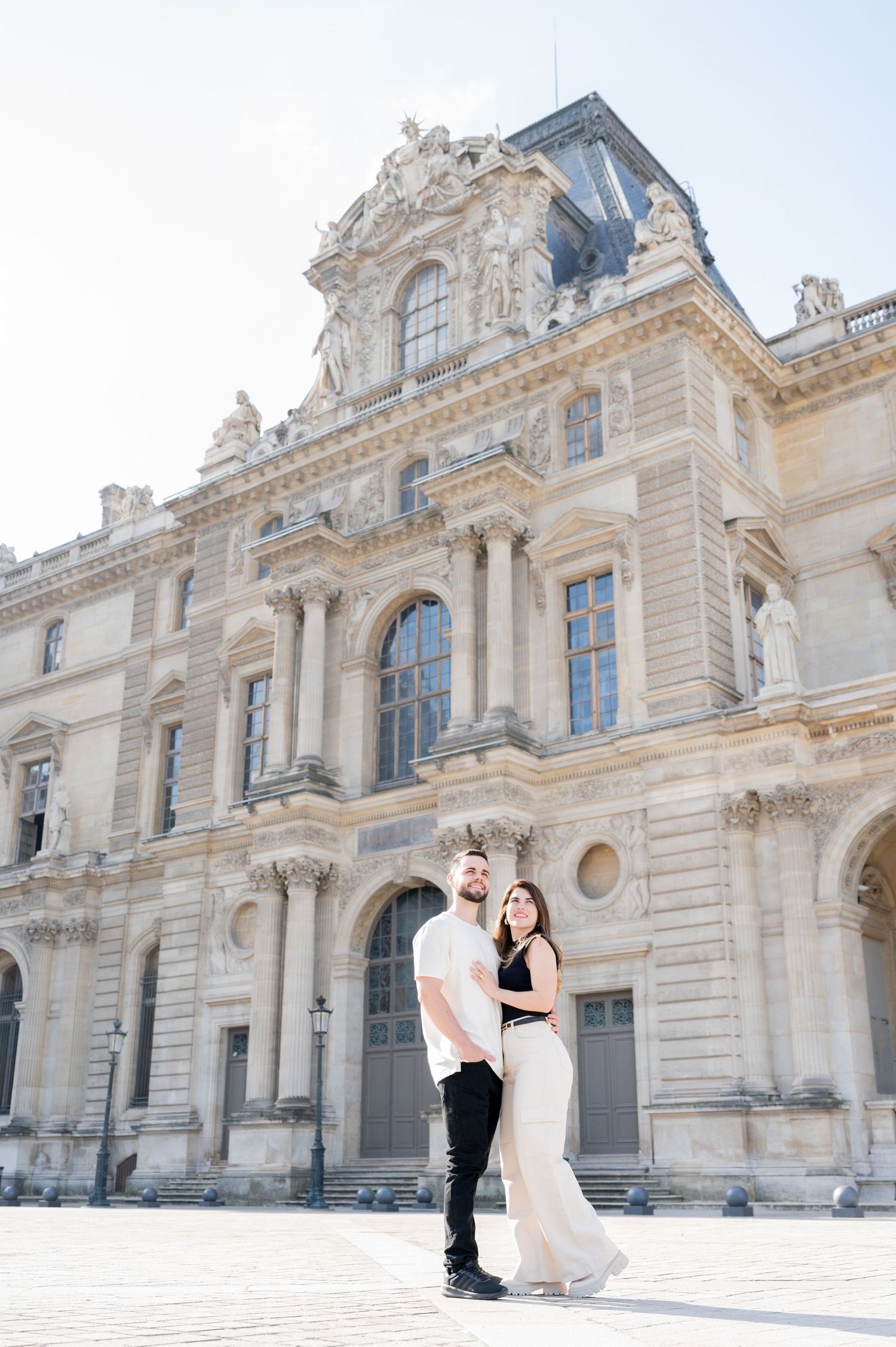 A romantic pose in front of an elegant French Renaissance building with ornate architectural details.