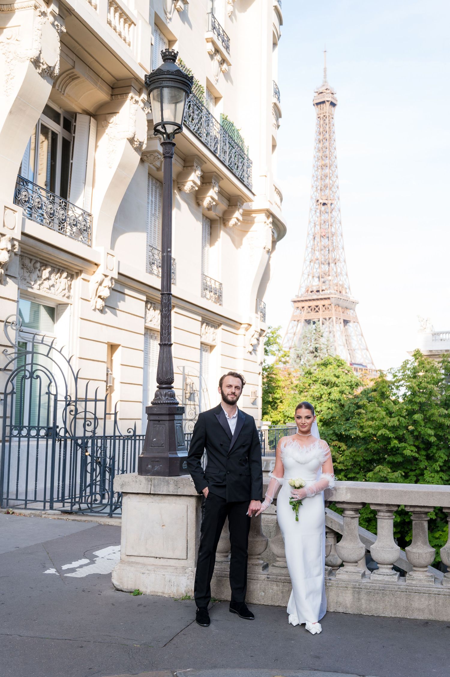 An elegant couple poses for wedding portraits on a classic Parisian street with the Eiffel Tower in view.