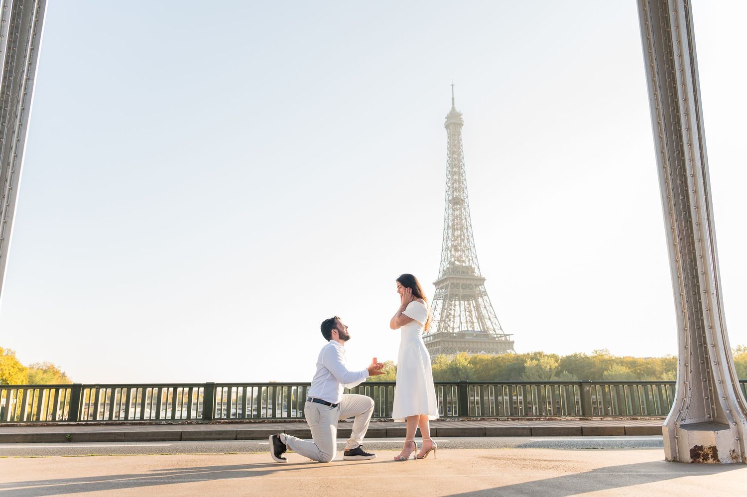 A panoramic view of the Eiffel Tower through columns with two people silhouetted against the Paris skyline.