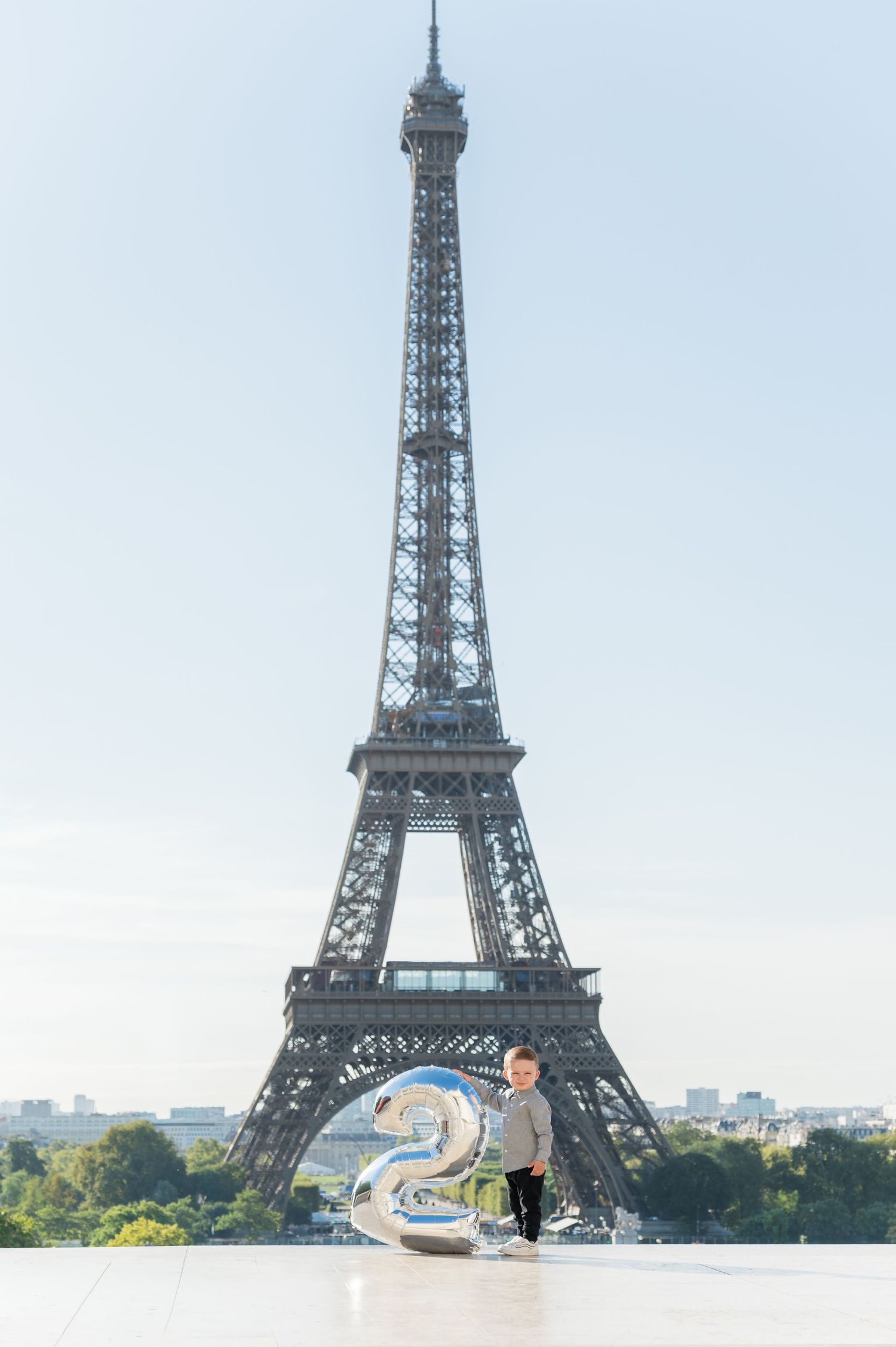 A couple poses together in front of the iconic Eiffel Tower in Paris during a golden sunset.