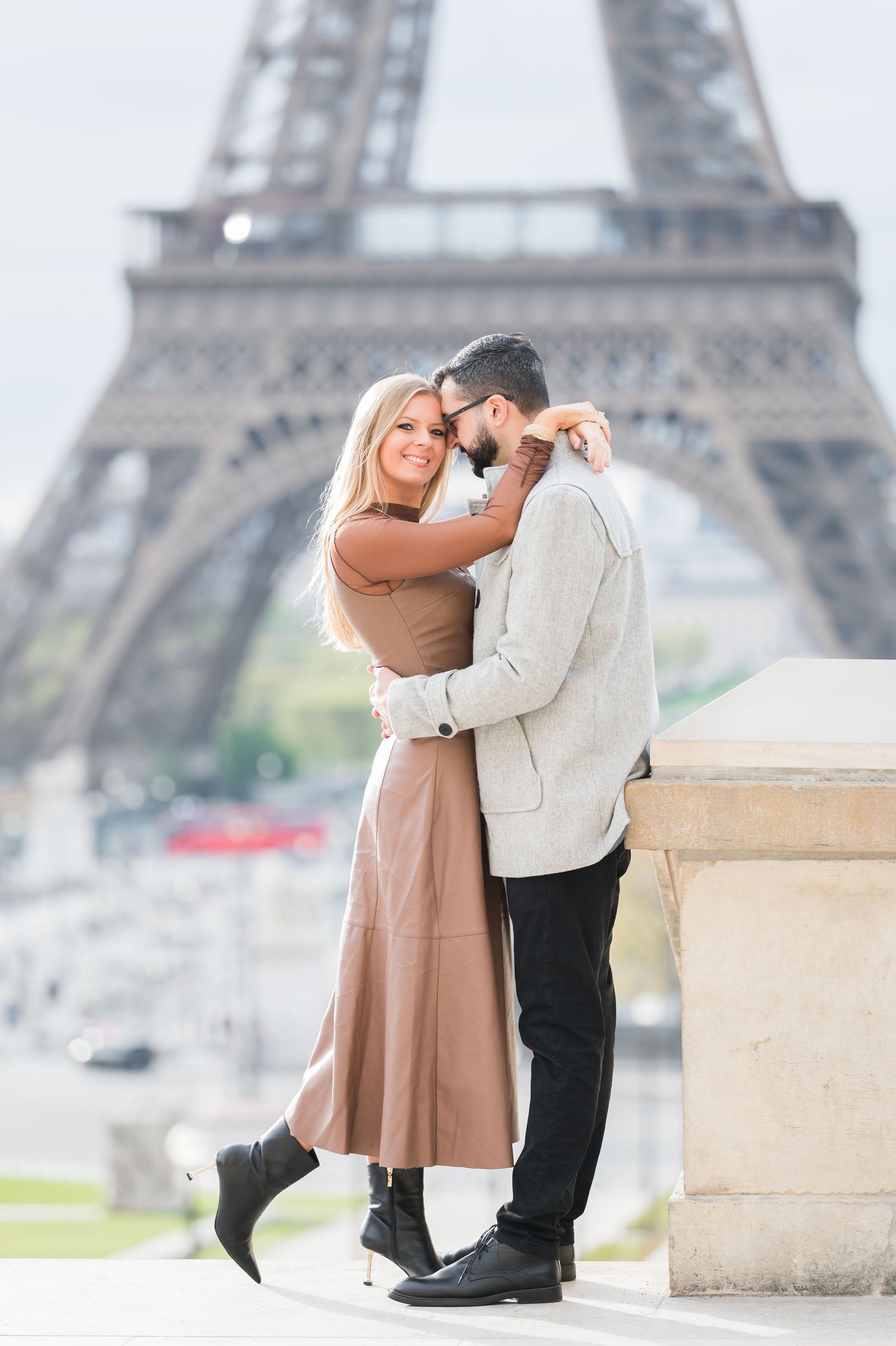 Romantic couple embracing in front of the Eiffel Tower in Paris, France on a beautiful day.
