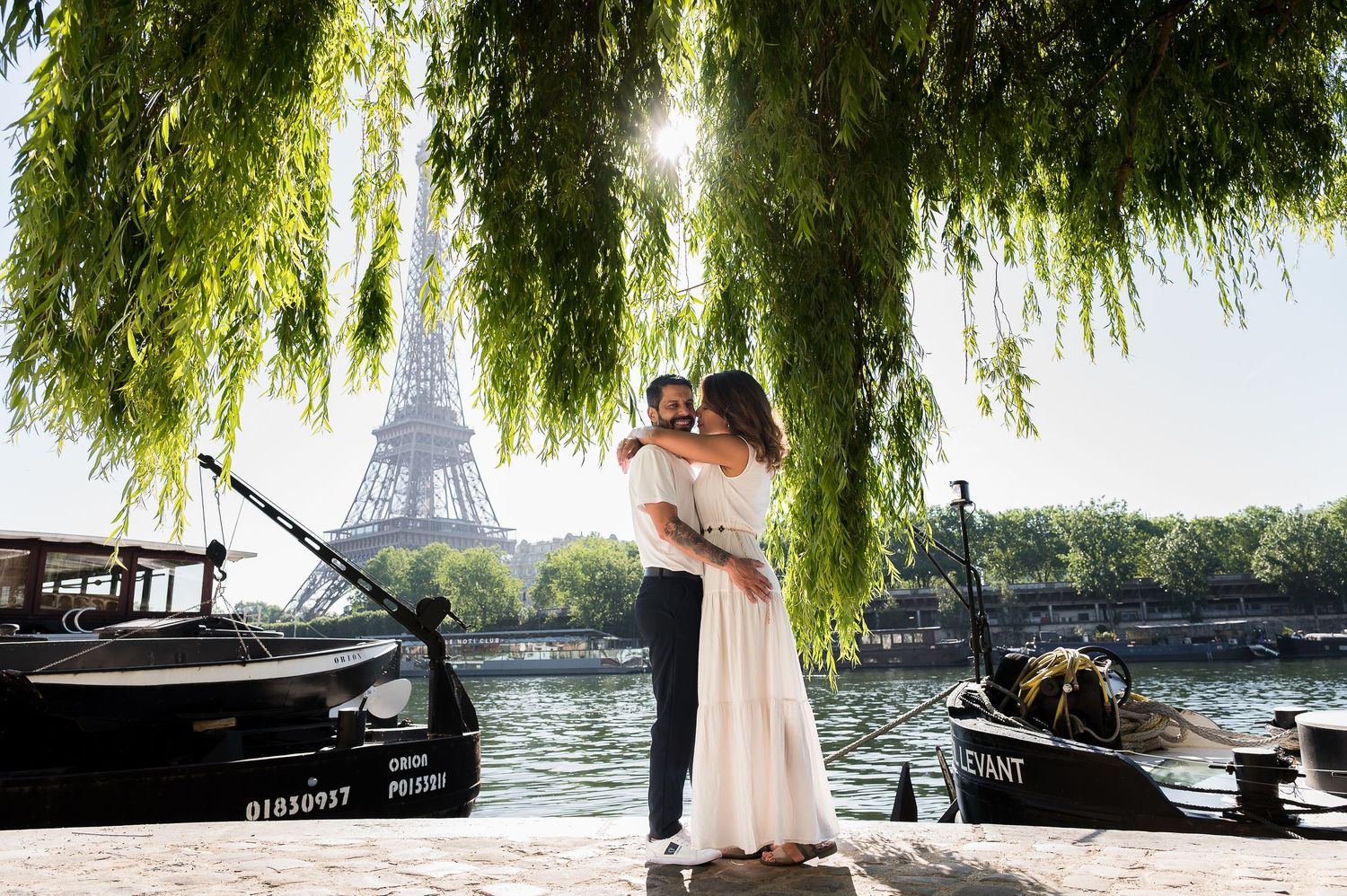 Couple embracing near the Seine River with the Eiffel Tower in the background, Paris, France.