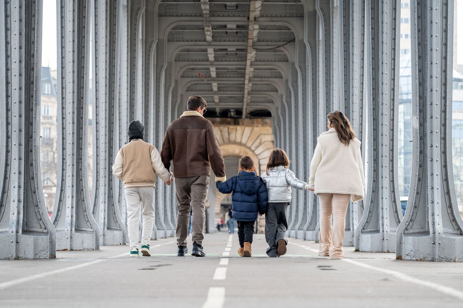 Group walking together on a bridge pathway framed by elegant architectural columns in Paris.