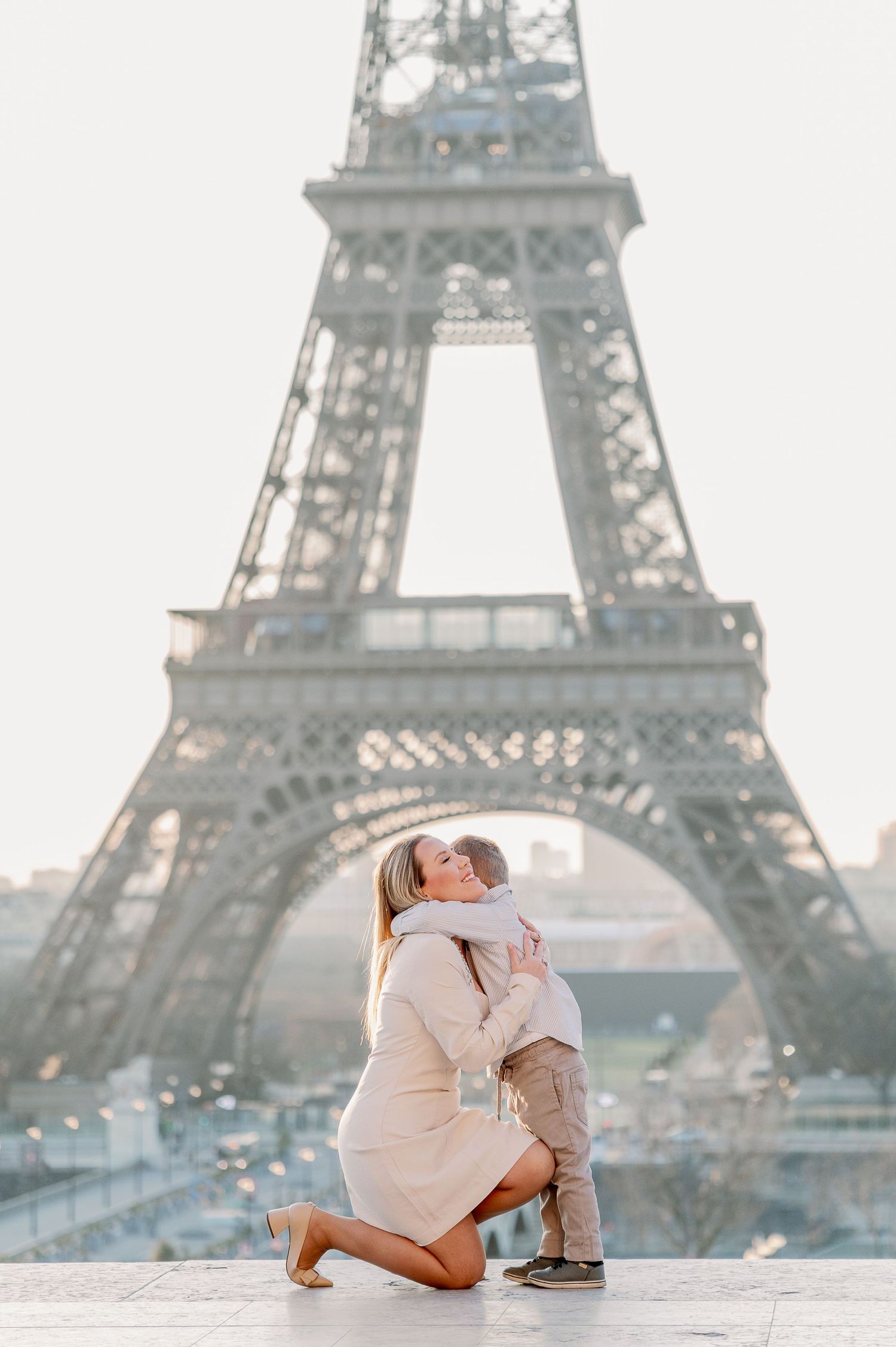 Tender family moment captured in front of misty Eiffel Tower.