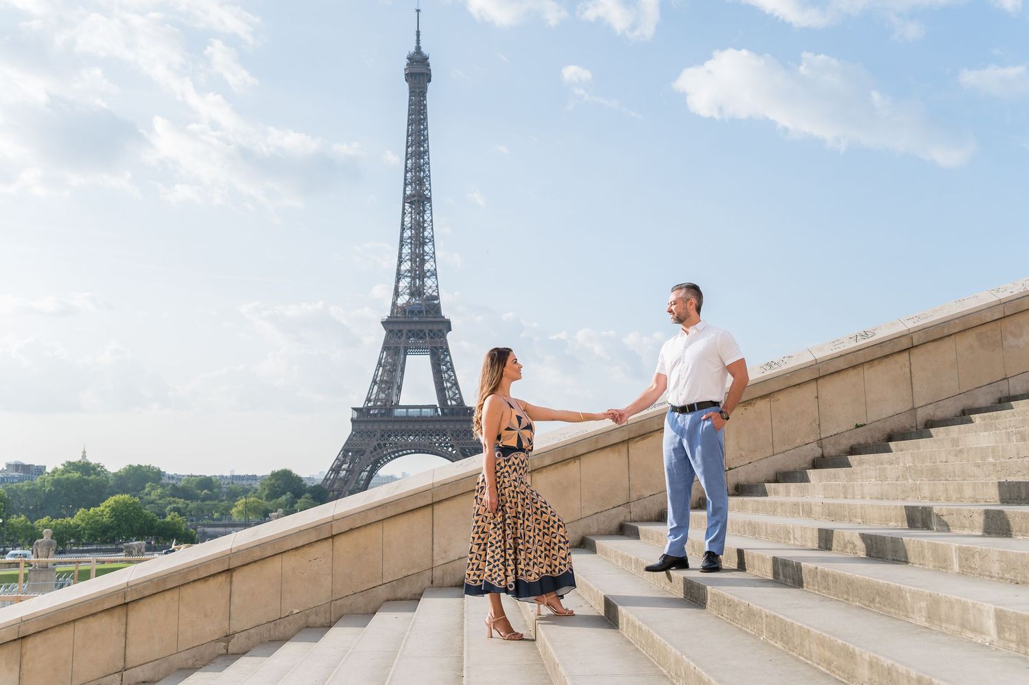 People sit on the steps of Trocadero Square in Paris while the iconic Eiffel Tower rises in the background.