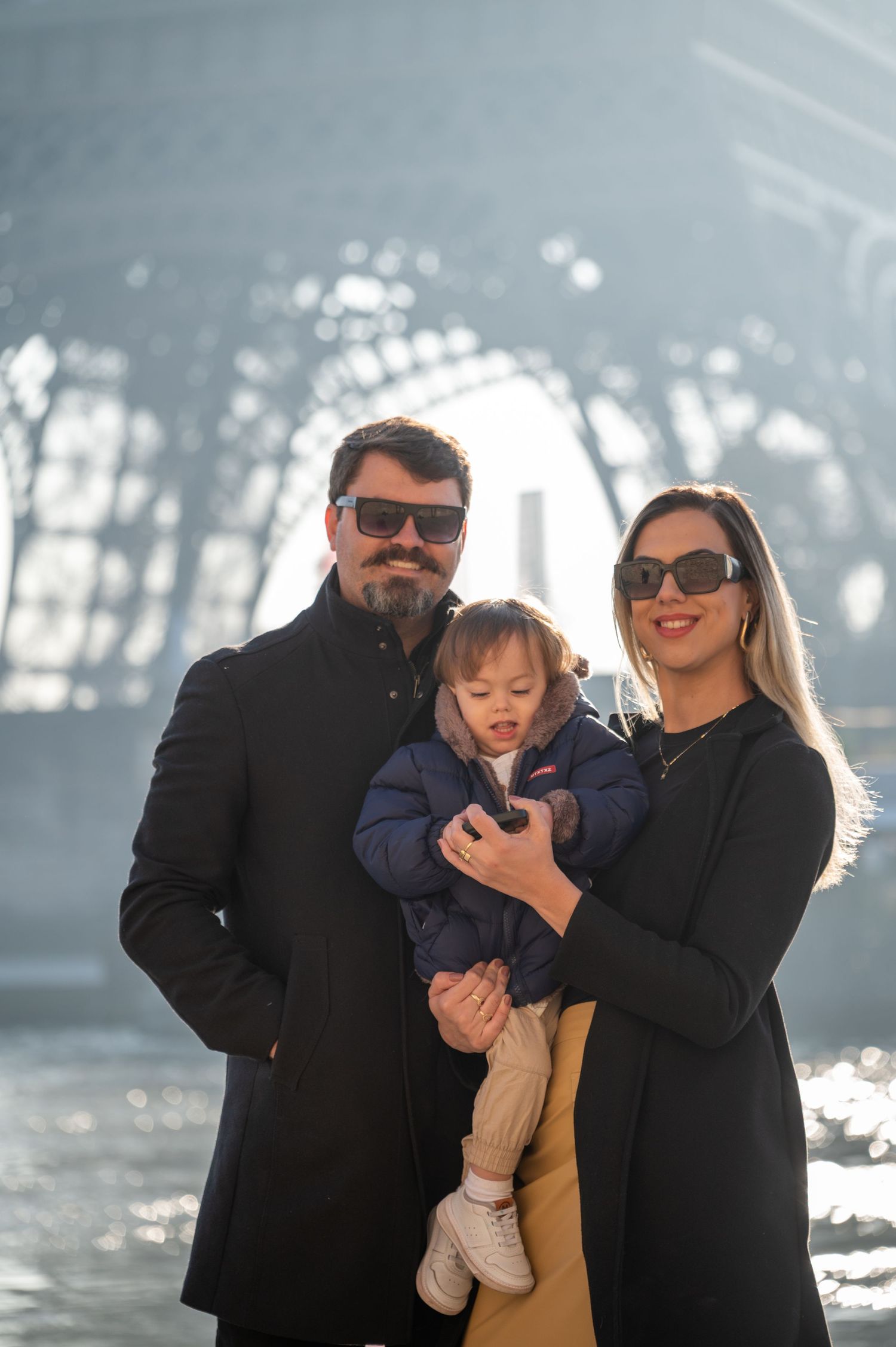 Winter family portrait beneath the iconic Eiffel Tower lattice structure.