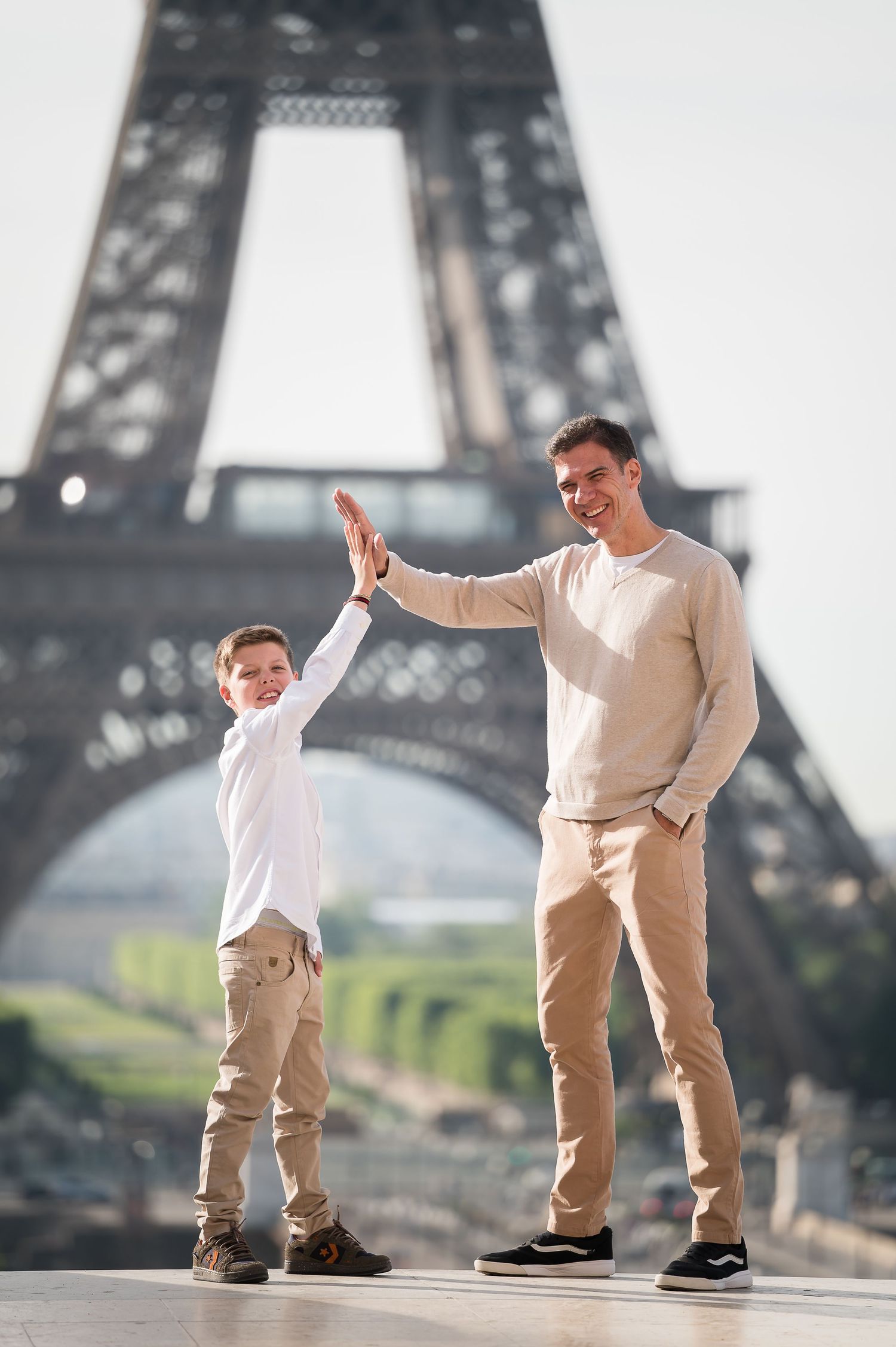Father and son giving high five in front of the Eiffel Tower in Paris, France.