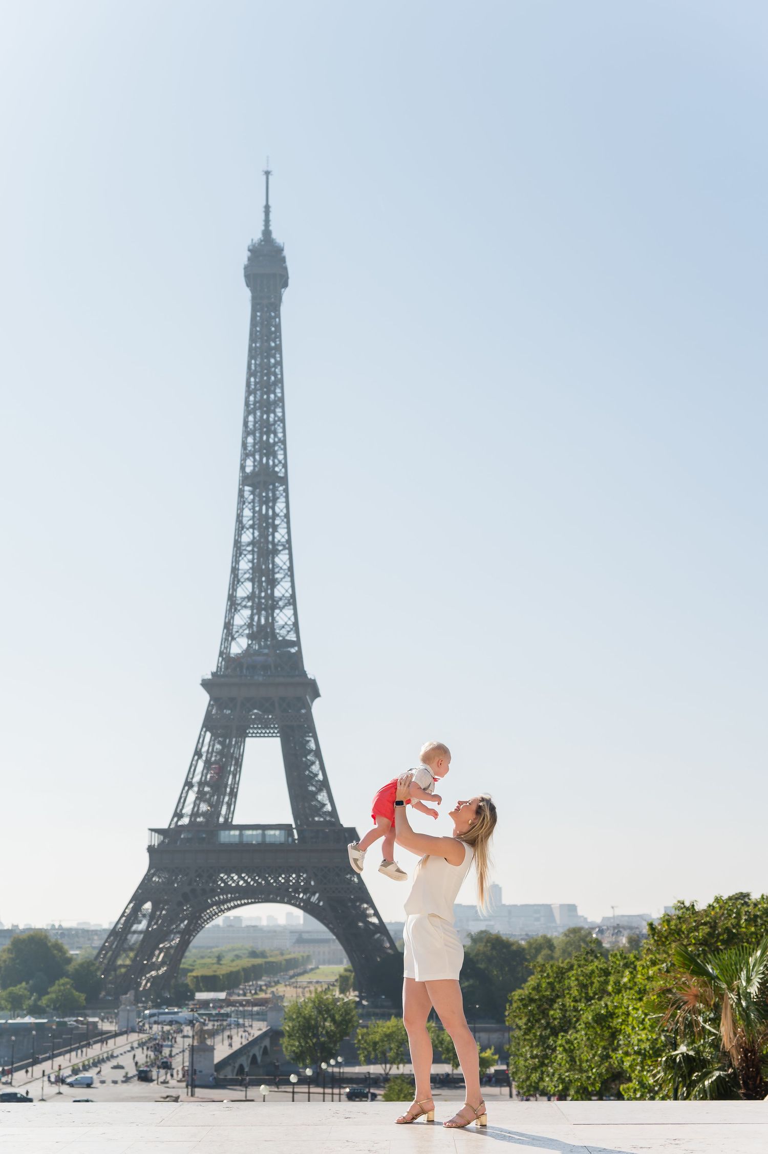 A couple shares a romantic moment in front of the iconic Eiffel Tower in Paris on a sunny day.