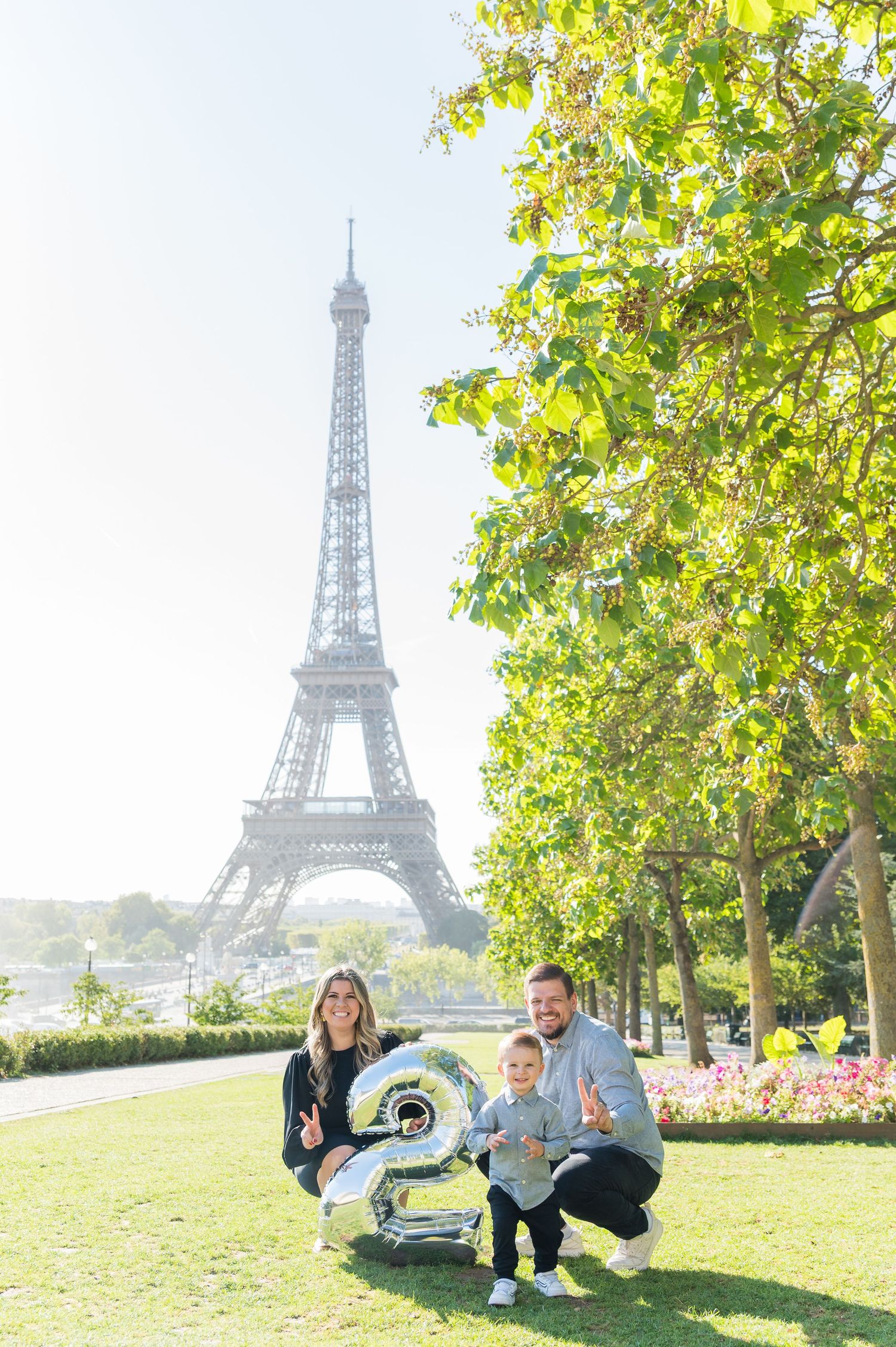Group relaxing on grassy hill with iconic Eiffel Tower visible in background on sunny Paris afternoon.