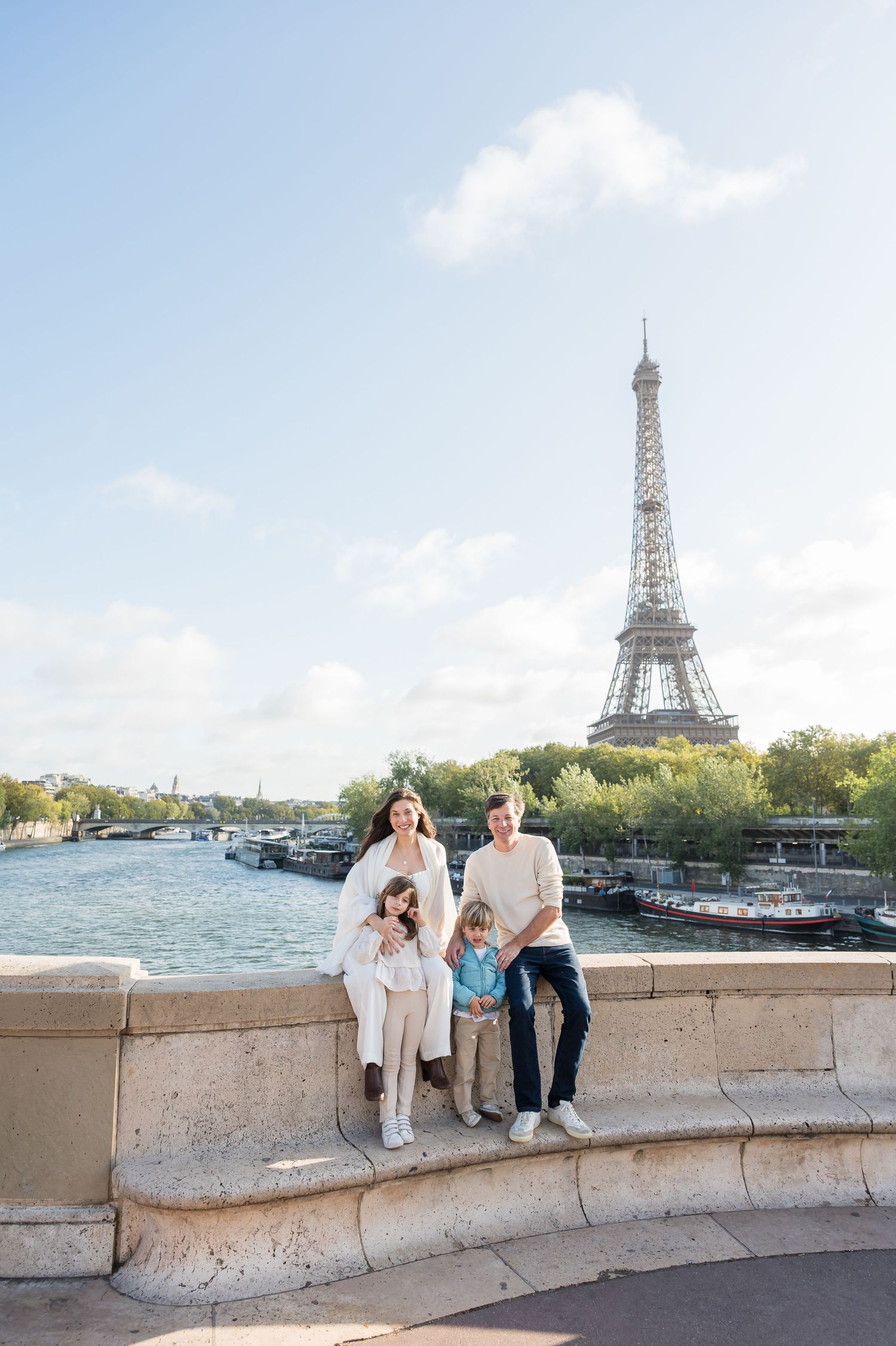 Family enjoying a beautiful day along the Seine River with the iconic Eiffel Tower visible in the Paris skyline.