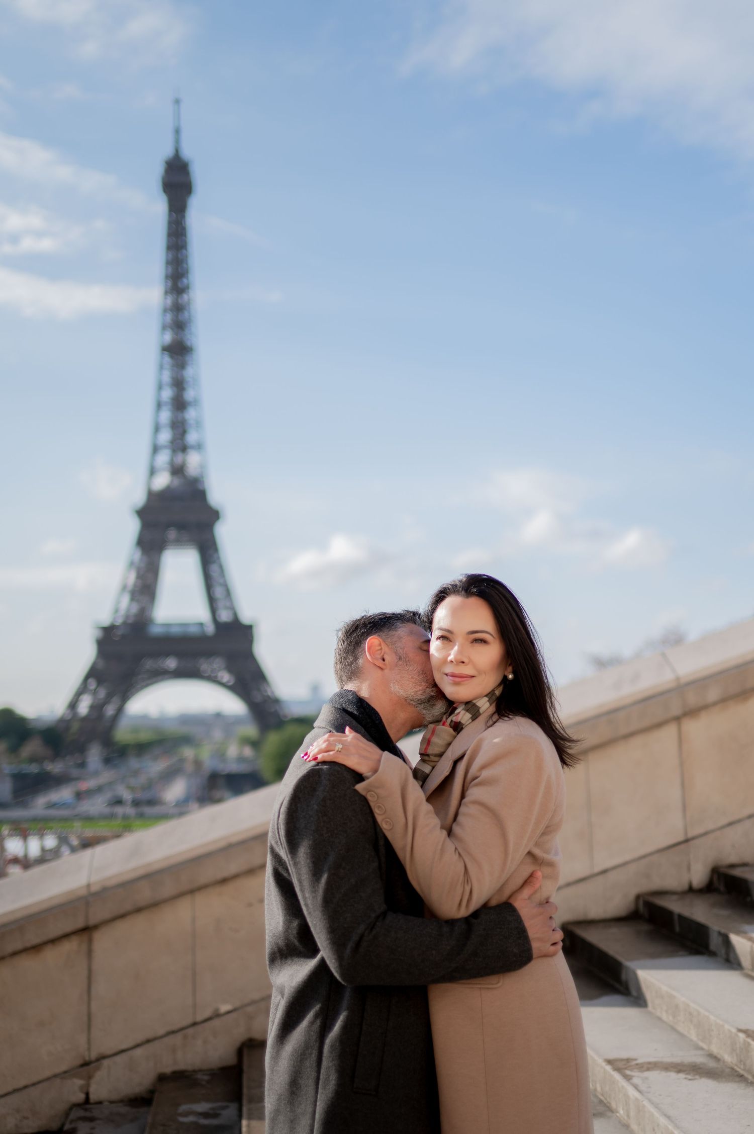 A romantic moment at Trocadero with the iconic Eiffel Tower in the background against a blue Parisian sky.