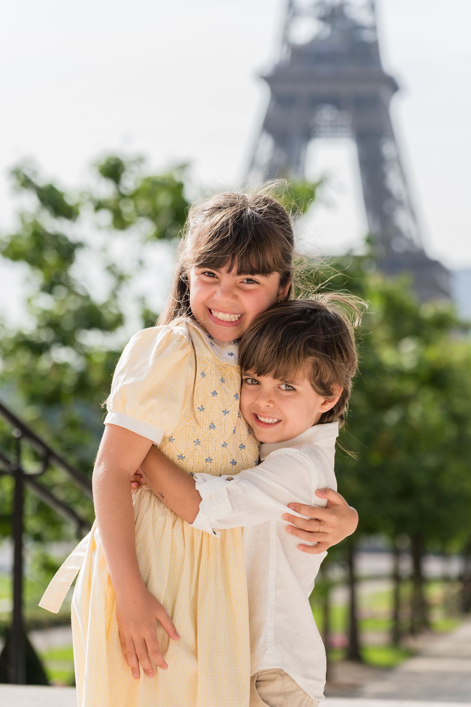 A playful piggyback moment captured in front of the Eiffel Tower on a sunny summer day in Paris.