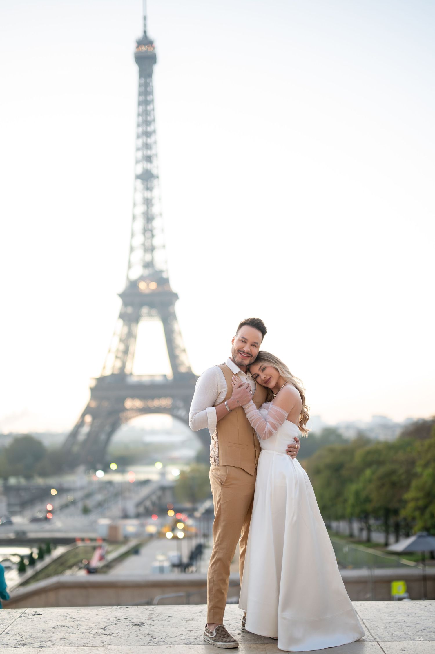 A romantic couple in wedding attire poses together with the iconic Eiffel Tower as their backdrop in Paris.