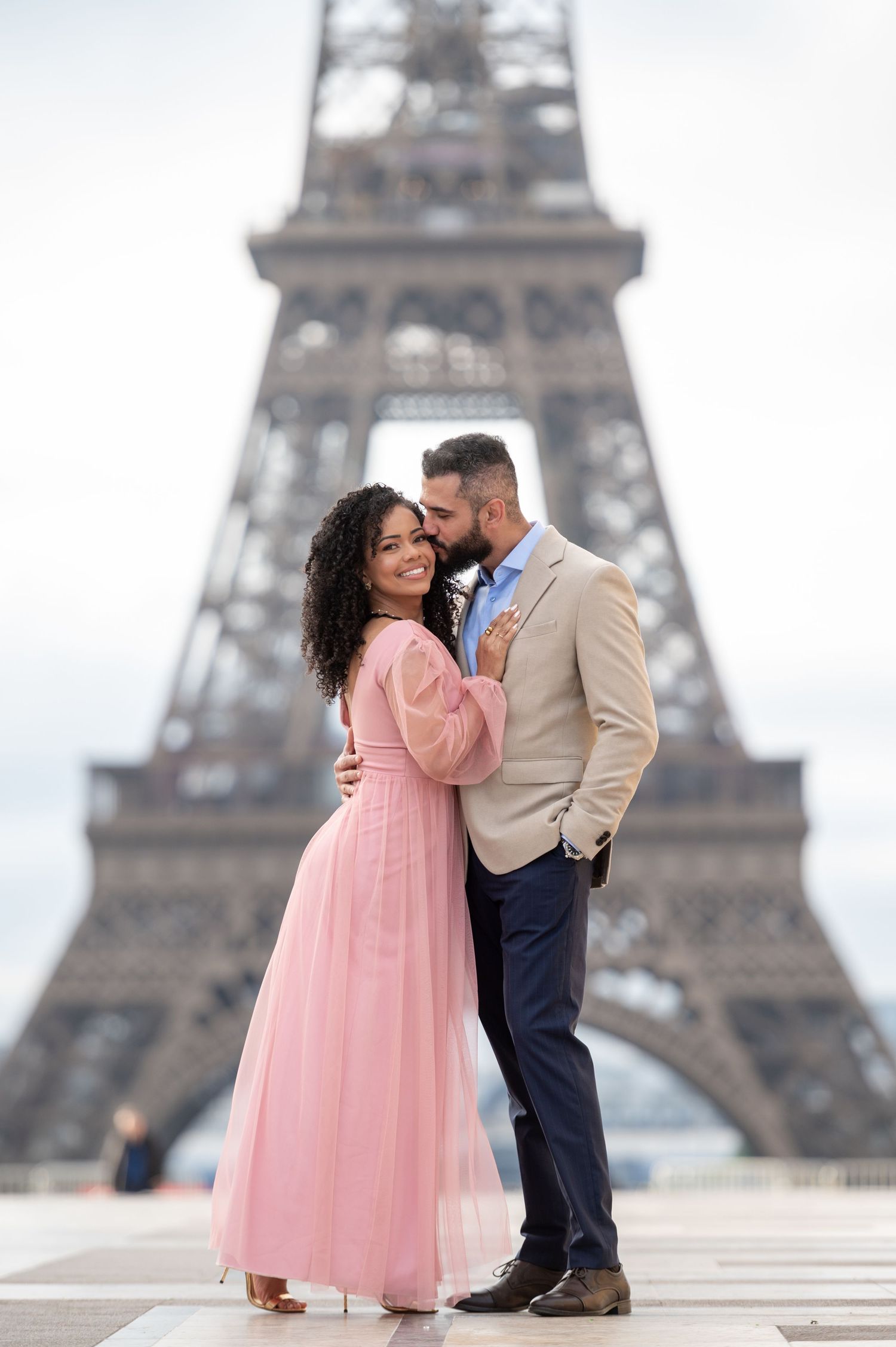 A romantic couple shares an intimate moment in front of the iconic Eiffel Tower in Paris.