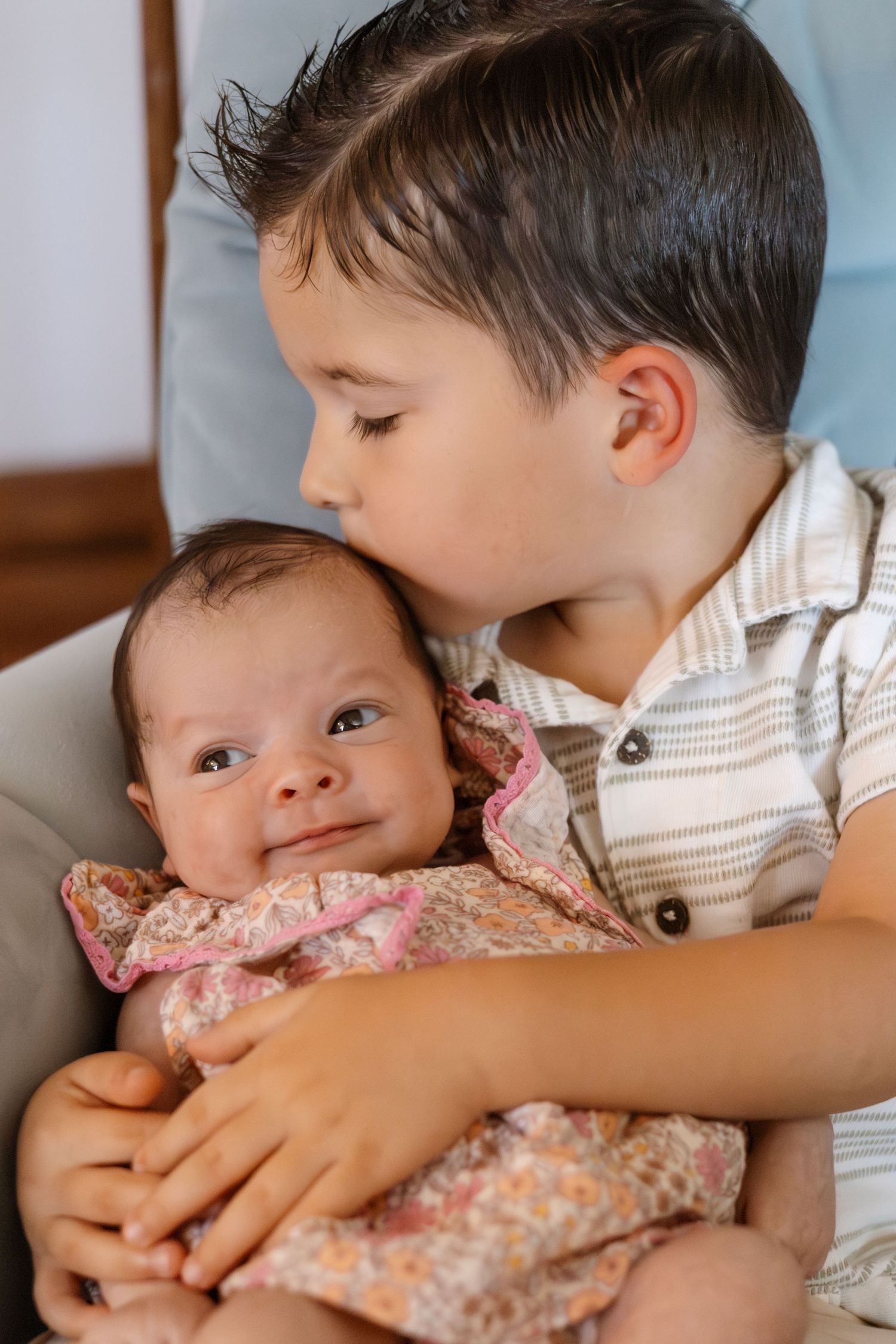 Two children sharing tender moment on blue couch.