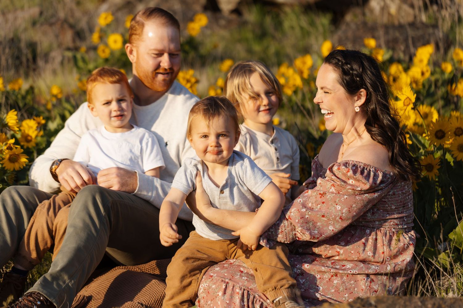 Family enjoying playful moments together in a field of yellow wildflowers at sunset.