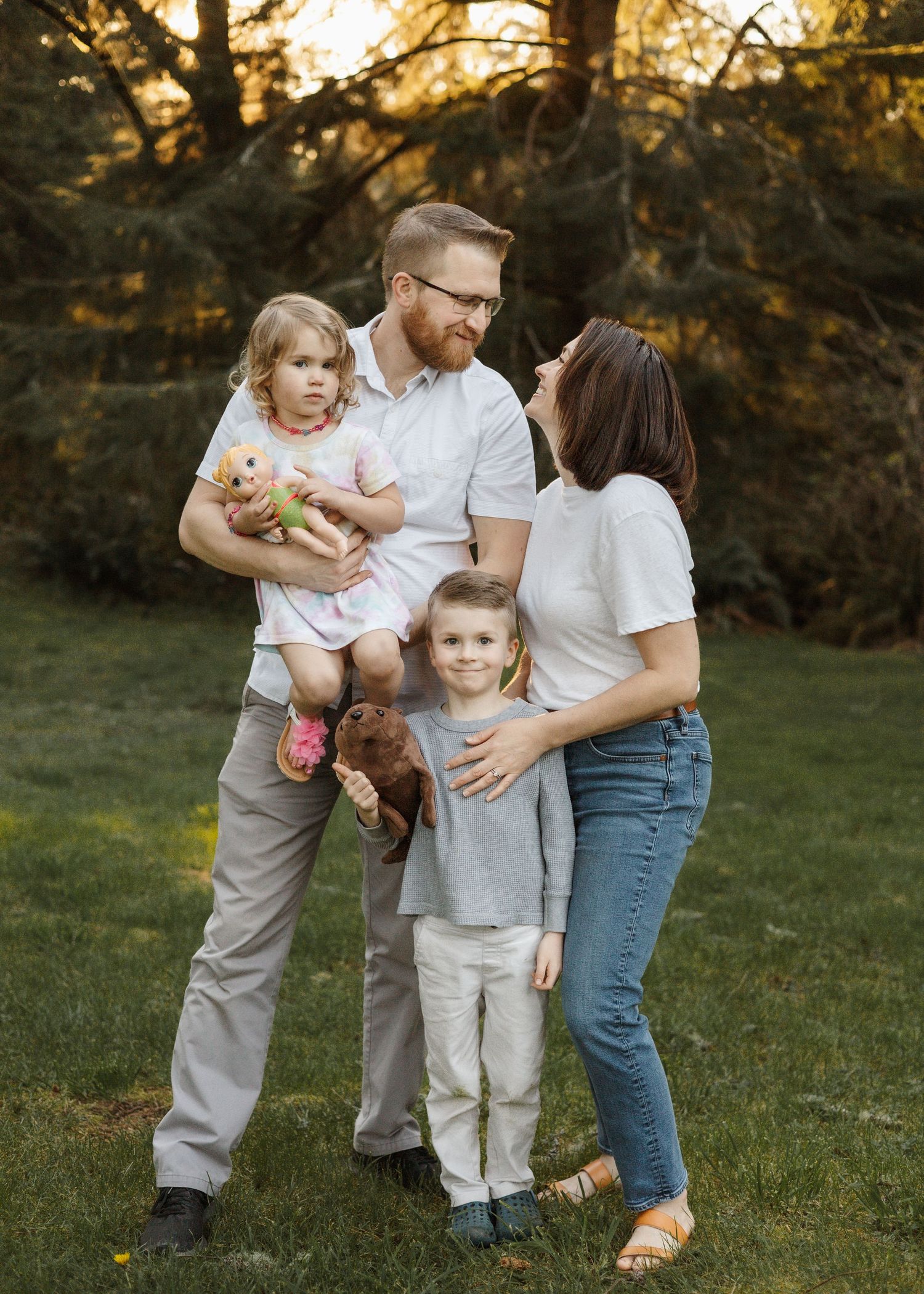 Family group interacts playfully together in outdoor setting during golden hour.