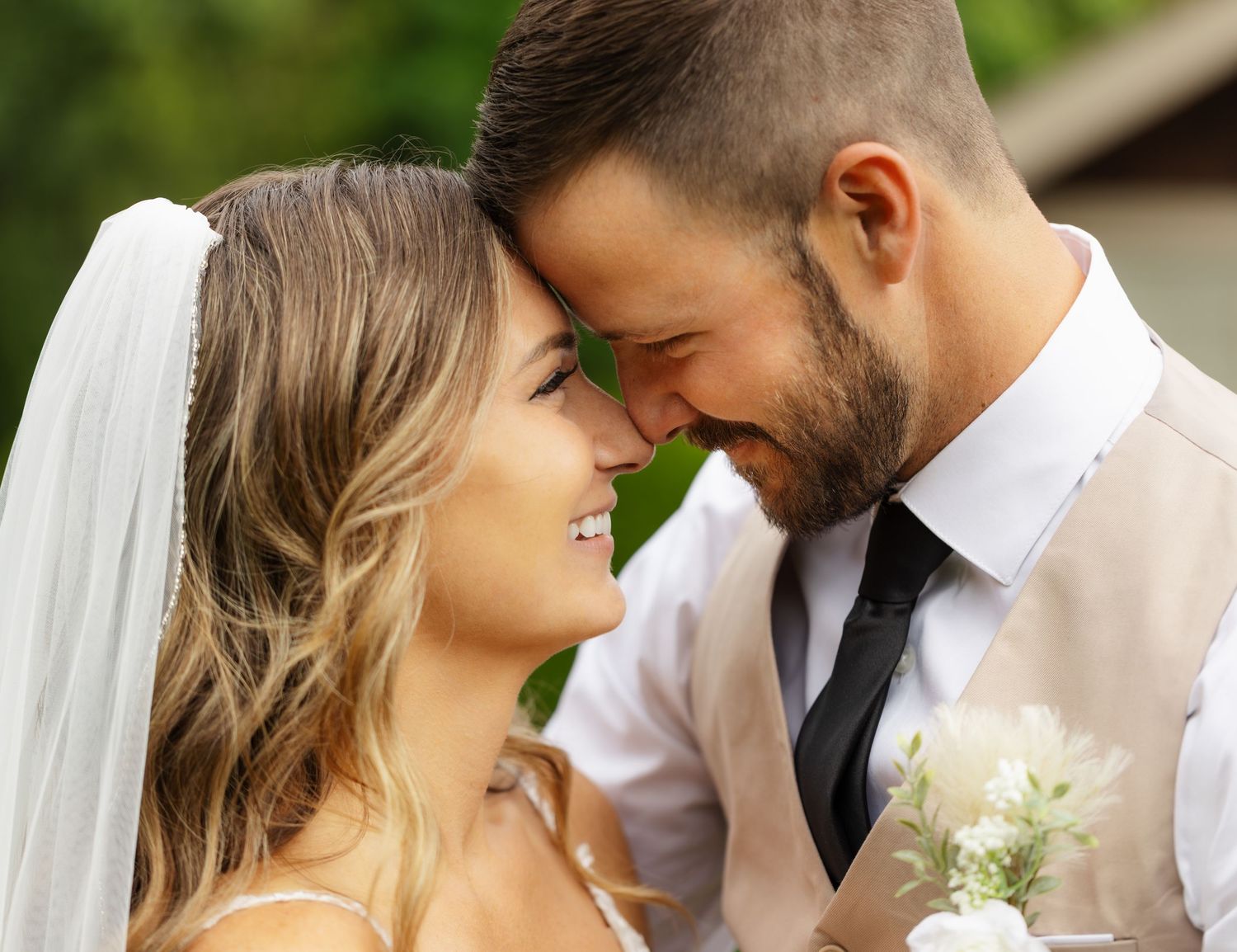 Romantic wedding couple shares intimate moments in garden setting with soft natural lighting and floral details.