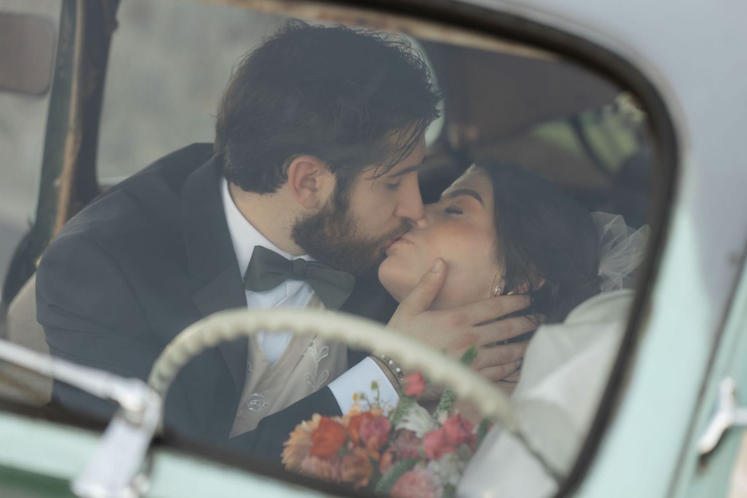A couple shares an intimate moment in a car, with red roses visible in the background.