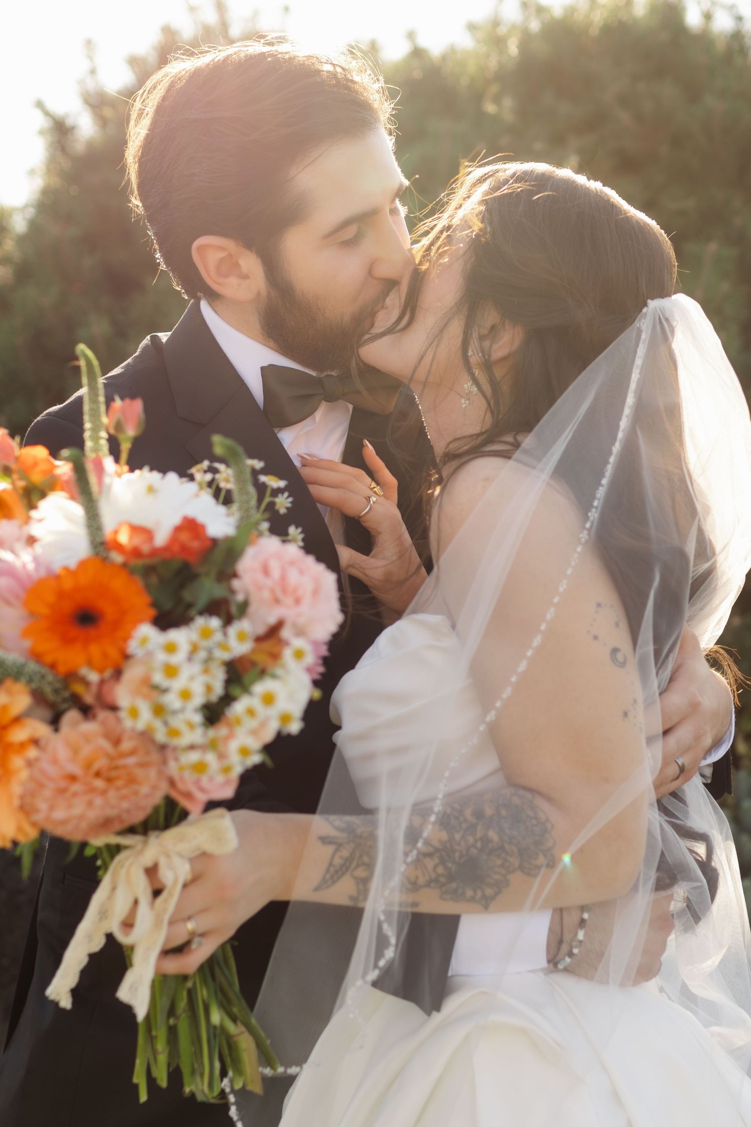 Romantic sunset wedding portrait with colorful orange and pink floral bouquet.