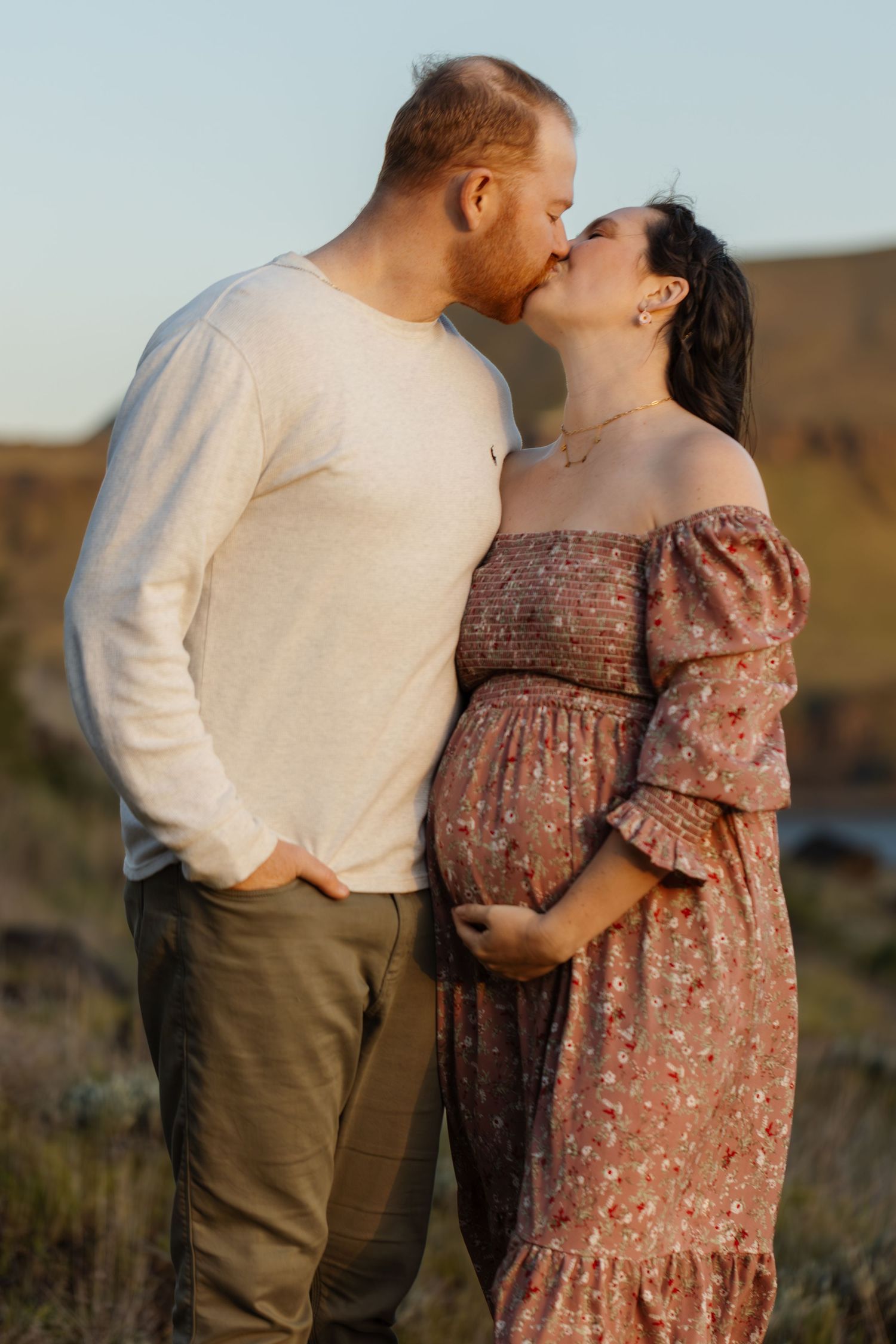 Intimate couple's portrait during sunset maternity session in natural setting.