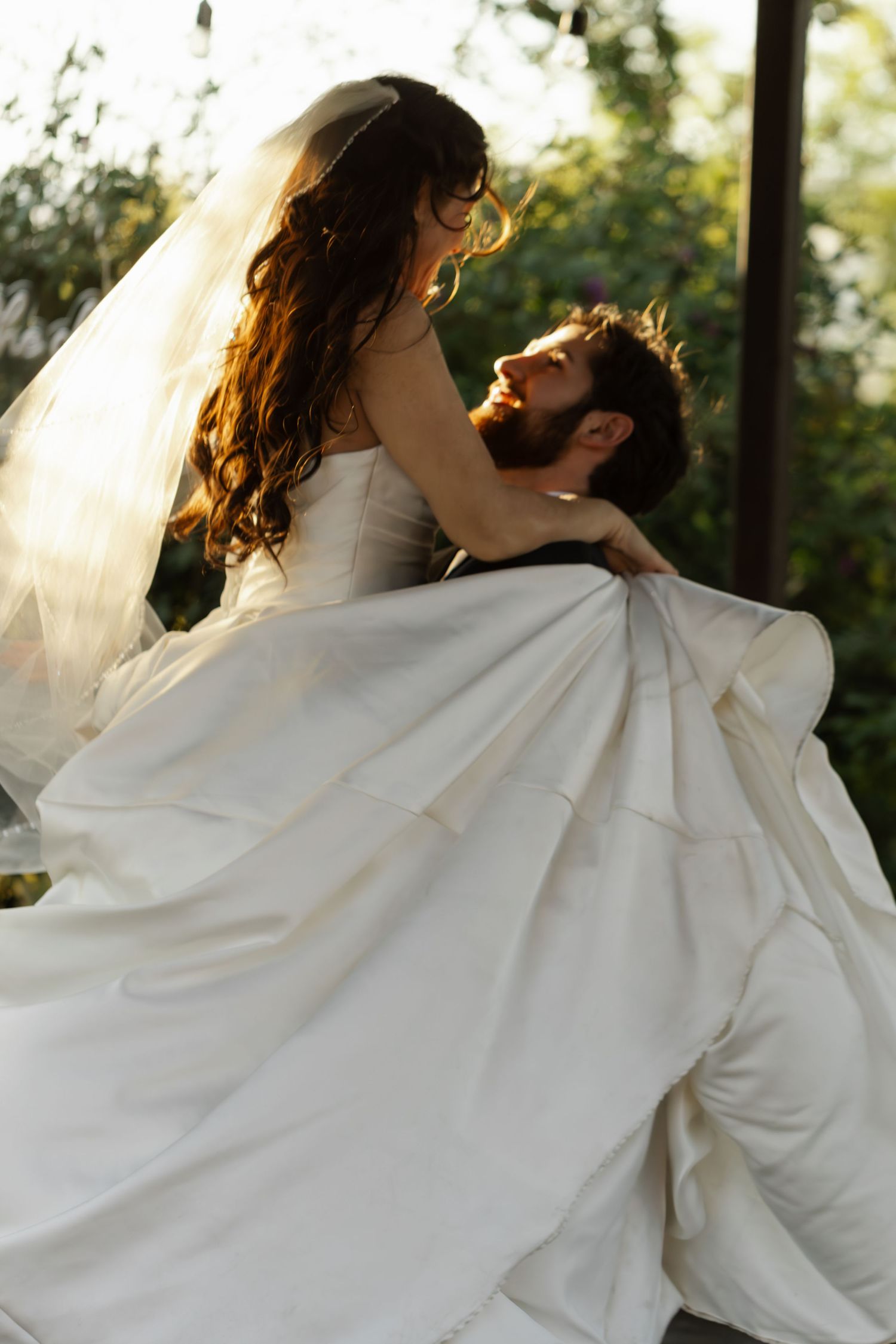 A couple shares an intimate dancing moment at sunset with the bride's white dress flowing in the breeze.
