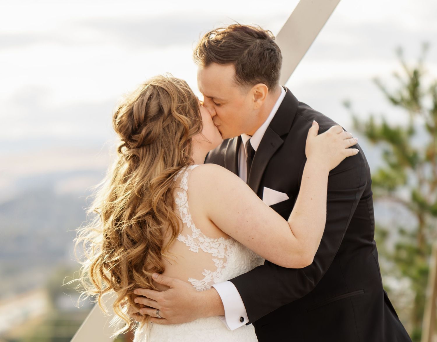 Romantic wedding couple embraces in a scenic mountain setting with dramatic lighting and flowing dress.
